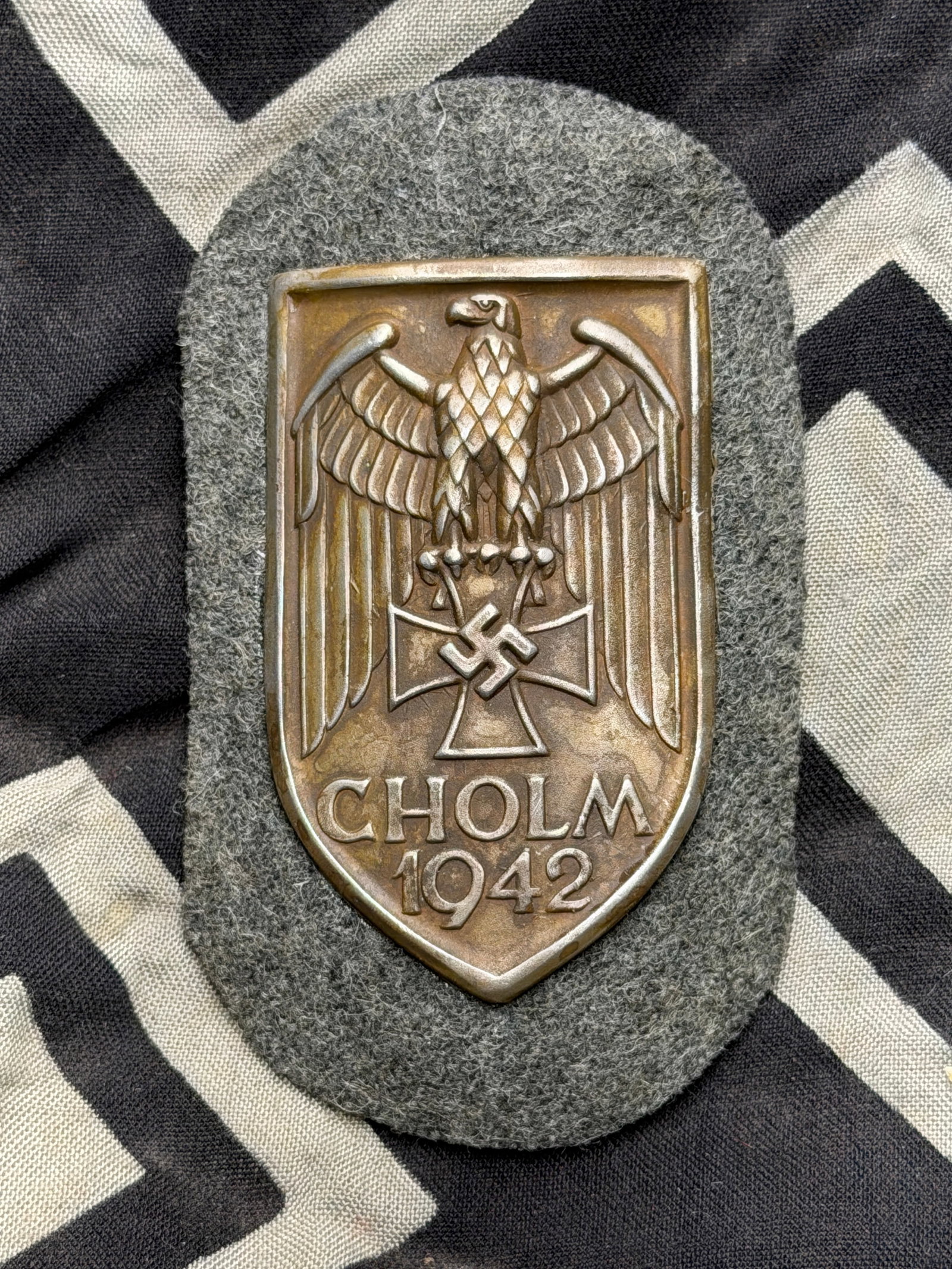 WW2 German Campaign CHOLM Shied Badge By F.A.B.: WW2 German Campaign CHOLM Shied Badge By F.A.B. Maker marked on the reverse. Shows good wear and use. Please view all detailed pictures. A rare example of the time period.