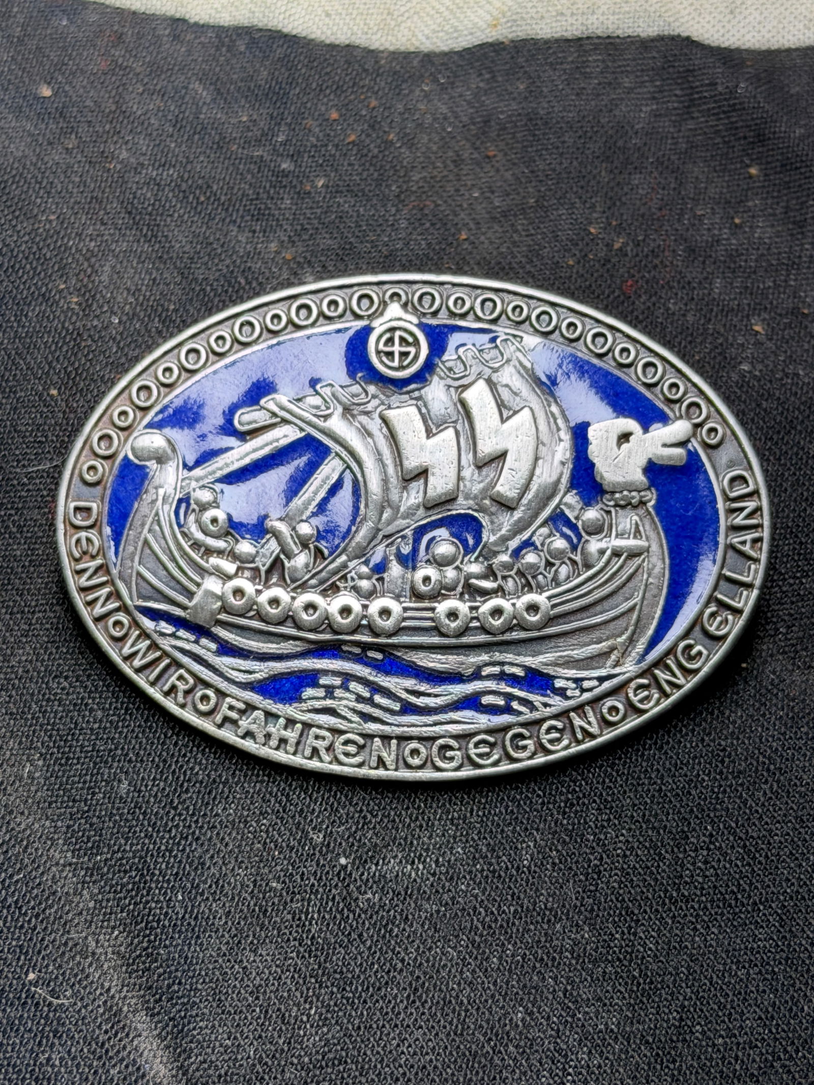 GERMAN WWII WAFFEN SS DIVISION WIKING BADGE BY GES. GESCH.: GERMAN WWII WAFFEN SS DIVISION WIKING BADGE BY GES. GESCH. A WWII Nazi German Third Reich Waffen SS Division Wiking enamel badge. The badge depicts a Viking ship with large SS runes on its sail over t