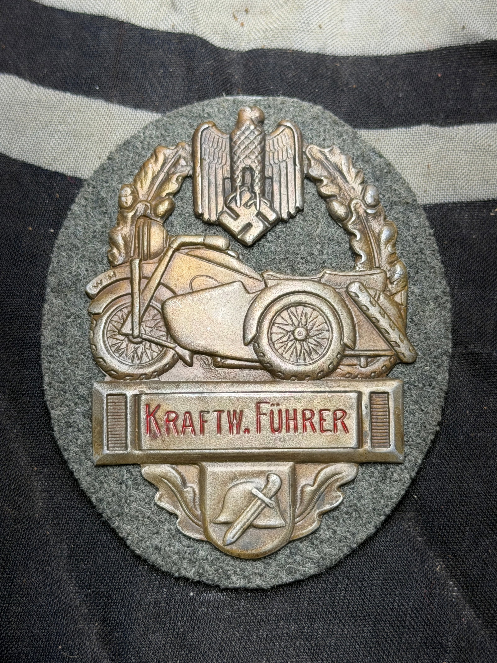 German WWII Army Kraftw Fuher Motorcycle Badge BY RZM 68: German WWII Army Kraftw Fuher Motorcycle Badge BY RZM 68. German WWII Army Kraftw Fuher Motorcycle Badge, measures 2 3/8” x 2 7/8” – has a thin horizontal safety pin back, stamped two pi