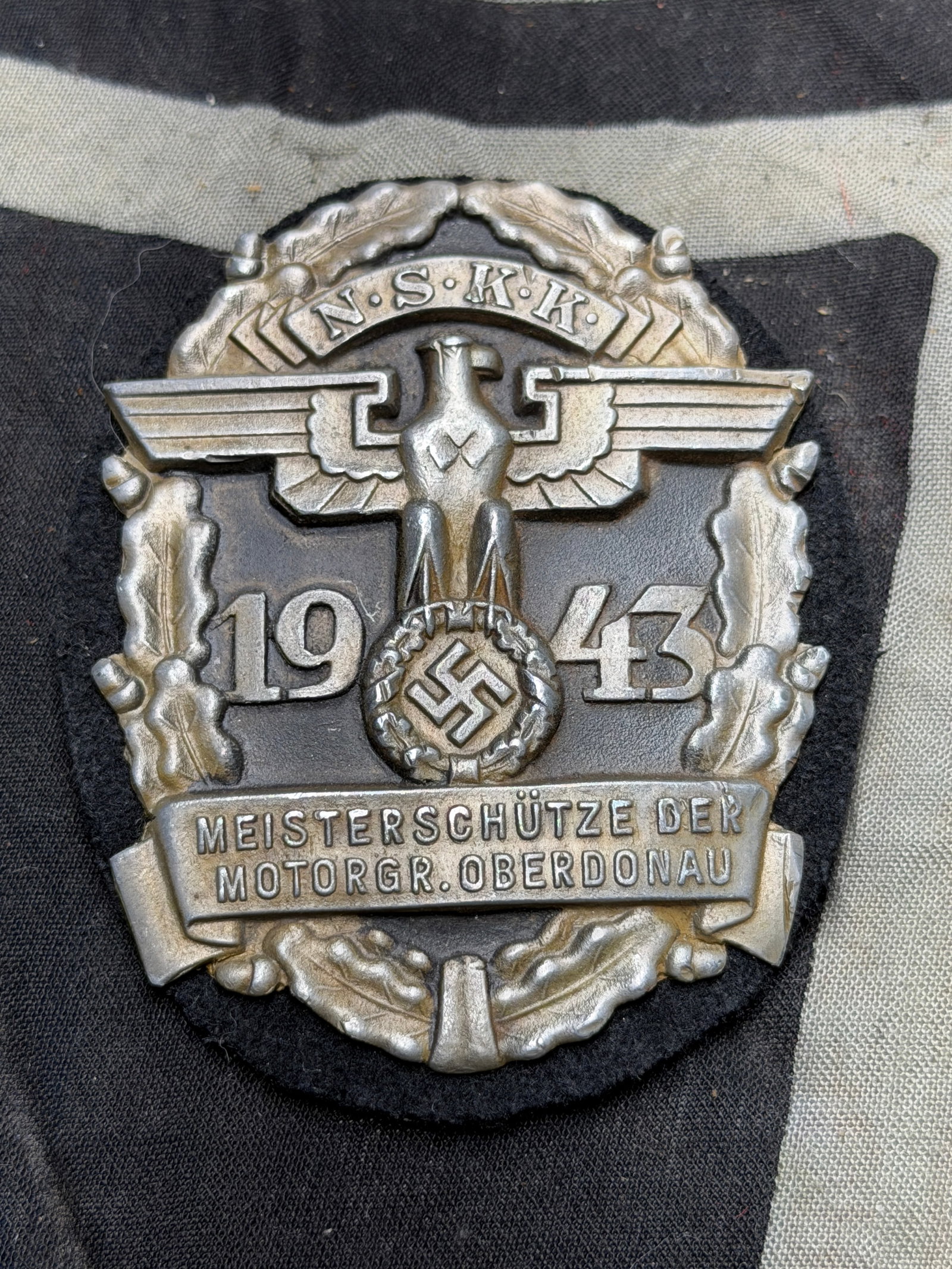 WW2 1943 German Steinhaur & Luck NSKK Meisterschutze / Marksman Badge RZM 63 Marked: Very nice WW2 1943 German NSKK Meisterschutze / Marksman Badge for the Motor Brigade Oberdonau made by Steinhaur & Luck, with their makers mark RZM 63. The badge measures 70 mm x 55 mm.