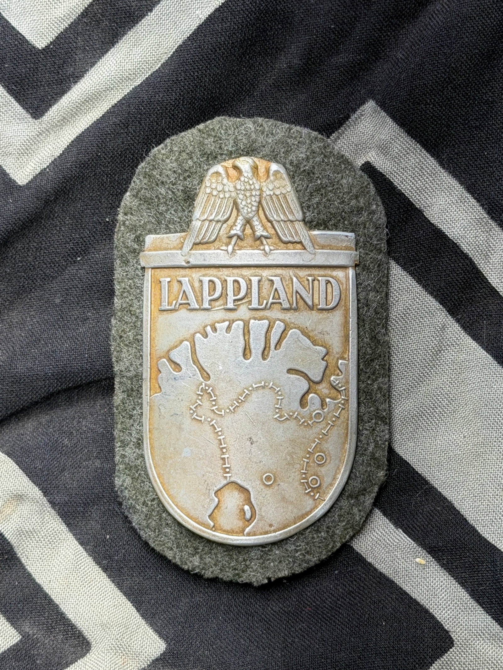 WW2 German Campaign LAPPLAND Shield By F.A.B.: WW2 German Campaign LAPPLAND Shield By F.A.B. A very rare find. Shows good wear and use with a beautiful overall patina. Please view all detailed pictures. A scarce example of the time period.