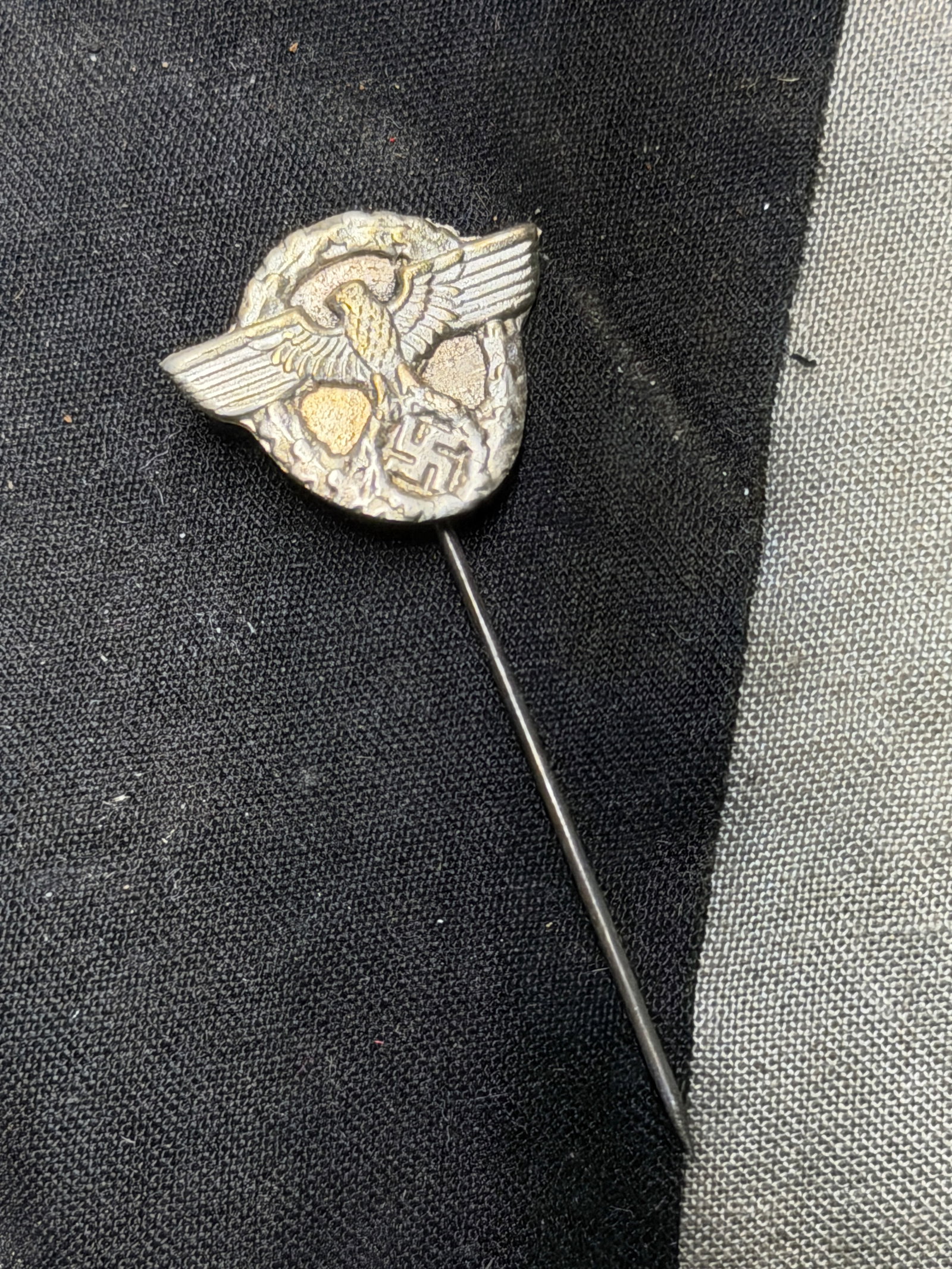 WW2 German Third Reich Stickpin (Eagle and Wreath Design): WW2 German Third Reich Stickpin (Eagle and Wreath Design). This is a small metallic stickpin featuring an eagle with outstretched wings clutching a swastika within a laurel wreath. The badge is mounte