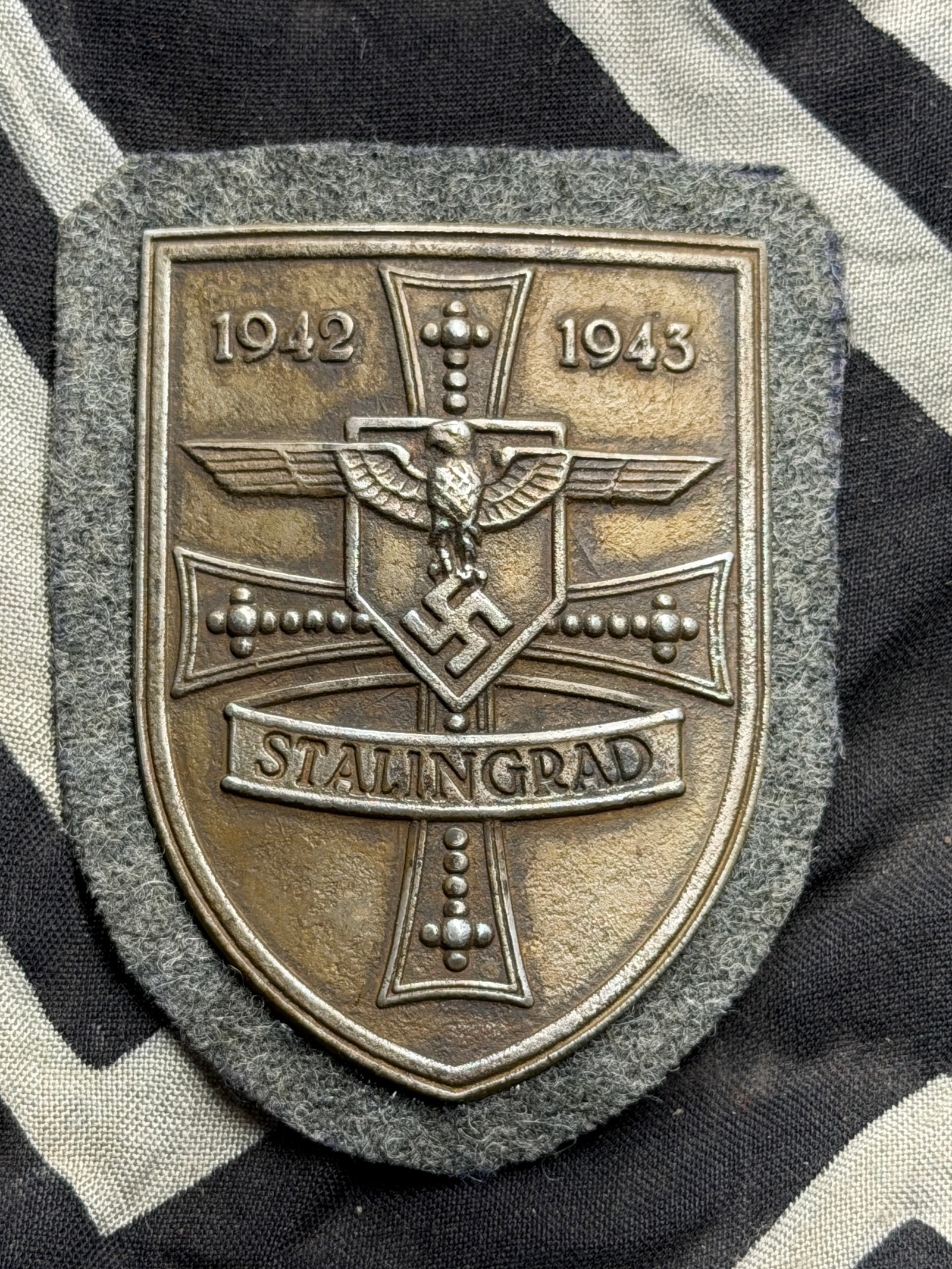 WWII GERMAN MILITARY AWARD STALINGRAD SHIELD BY F.A.B.: WWII GERMAN MILITARY AWARD STALINGRAD SHIELD BY F.A.B. A WWII Nazi German military decoration, the Stalingrad Shield. The zinc shield shaped badge features an eagle with swastika, a cross and inscript