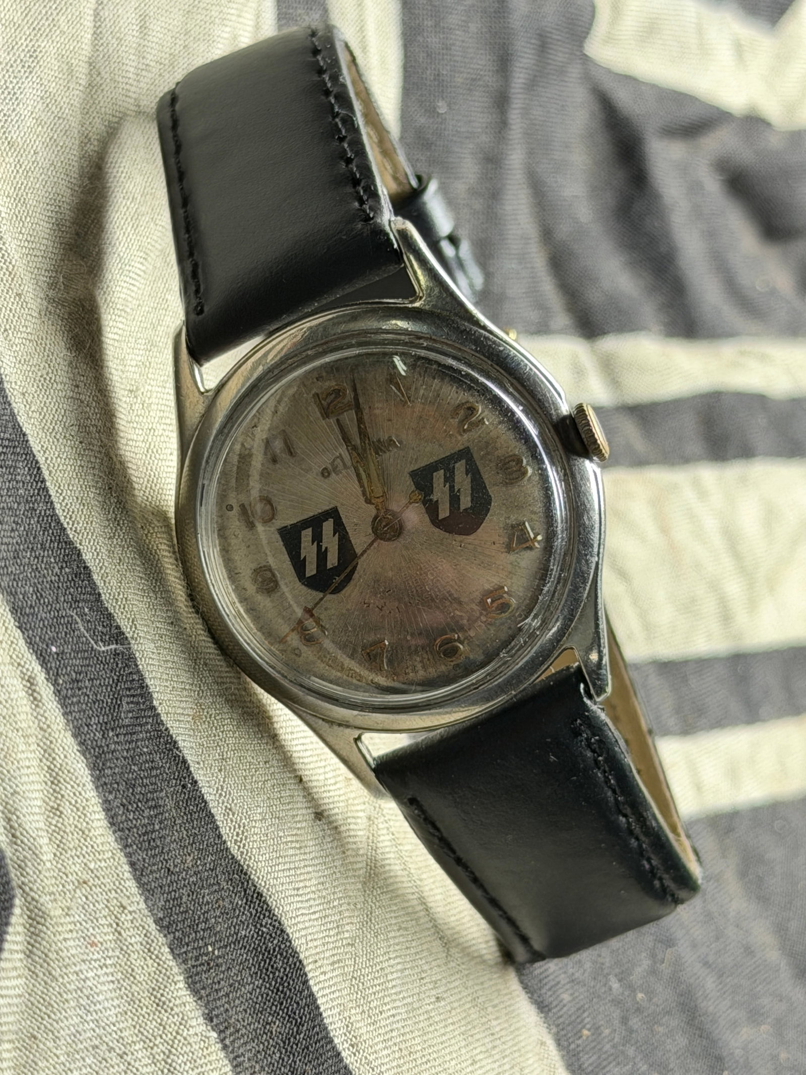 GERMAN WWII MODEL WAFFEN SS WRIST WATCH: GERMAN WWII MODEL WAFFEN SS WRIST WATCH. A WWII Nazi German model Waffen SS 17 Jewels wrist watch. Swiss made. A white enamel dial with Arabic numerals and gold tone hands, and enameled SS runes, to t