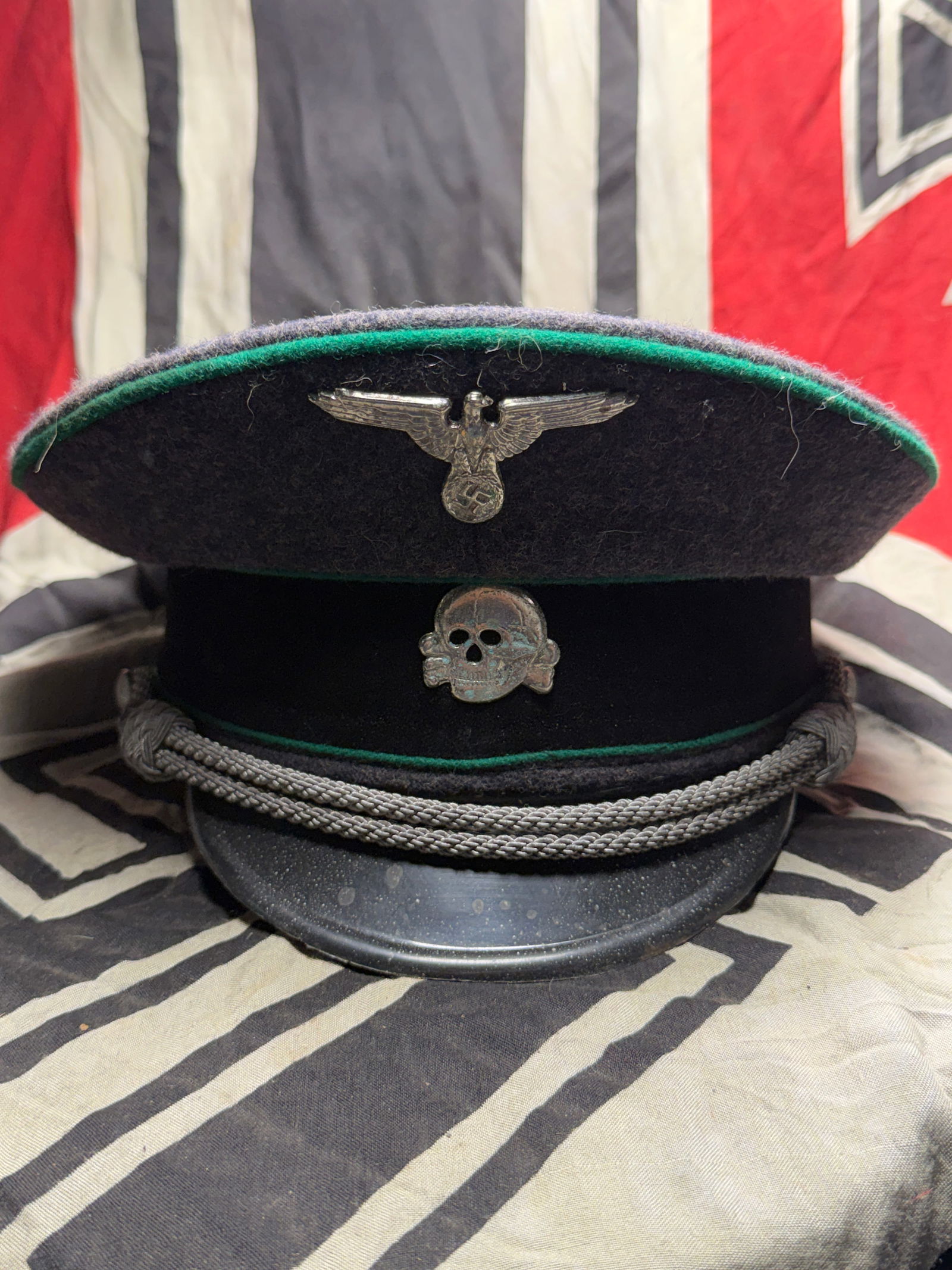 WW2 German SS officers wool visor cap Gebirgsjager With RZM Paper Tag: WW2 German SS officers wool visor cap Gebirgsjager With RZM Paper Tag. A rare field grey wool features green Waffenfarbe piping. Metal eagle with metal skull attached with chin chord and two pebble si