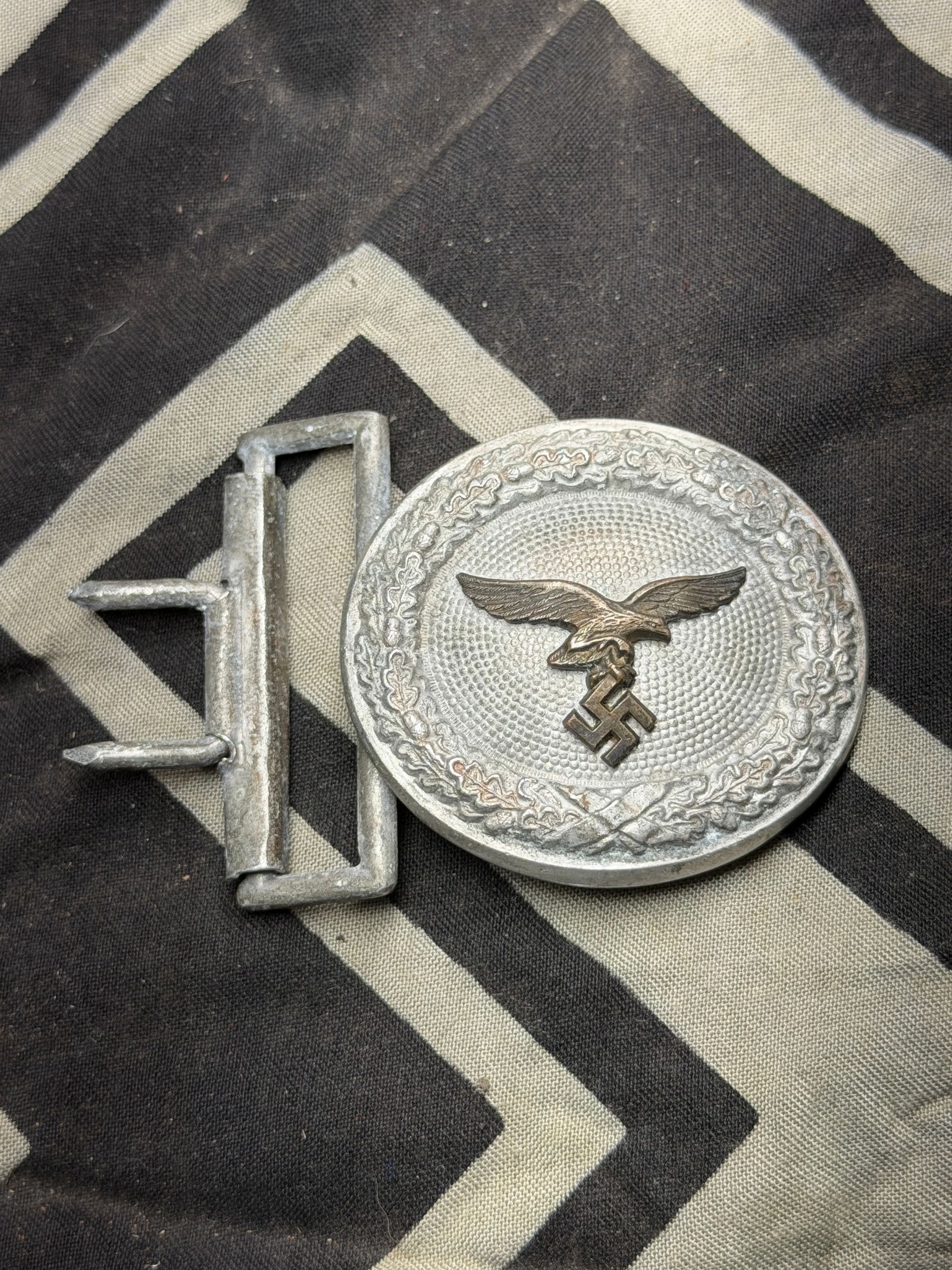 WW2 Germany Luftwaffe An Officer’s Belt Buckle: WW2 Germany, Luftwaffe An Officer’s Belt Buckle. Constructed of aluminum, the obverse consisting of an oval oak leaf wreath, joined together at the bottom by ribbon, surrounding a central raised and