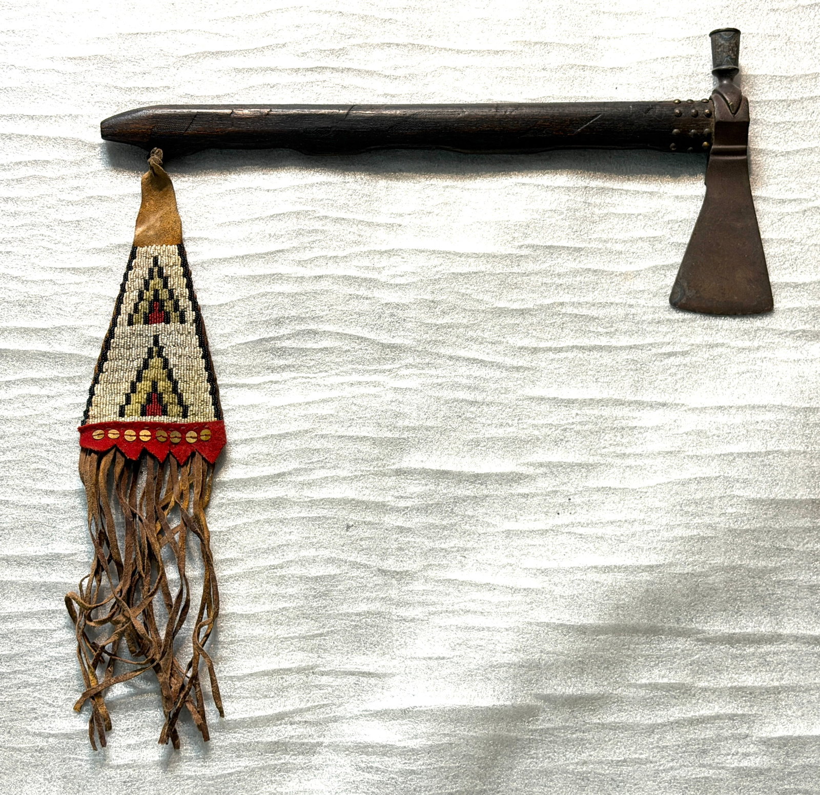 Native American Pipe Tomahawk with Beaded Drop – 19th Century Plains Style: Presented here is an authentic Native American pipe tomahawk, a finely crafted combination of both weapon and ceremonial peace pipe, originating from the Plains region and dating to the 19th century. 