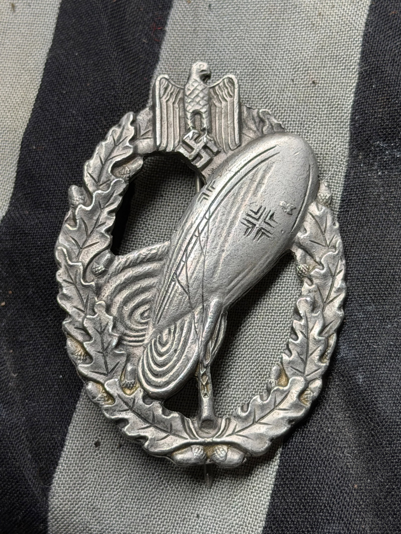 WW2 German Luftschiffer Badge (Airship Pilot/Observer Award) circa 1930s–1945 Marked SW: WW2 German Luftschiffer Badge (Airship Pilot/Observer Award) circa 1930s–1945 Marked SW. This oval aluminum badge, measuring approximately 2 inches in height, features a dirigible (airship) in fligh