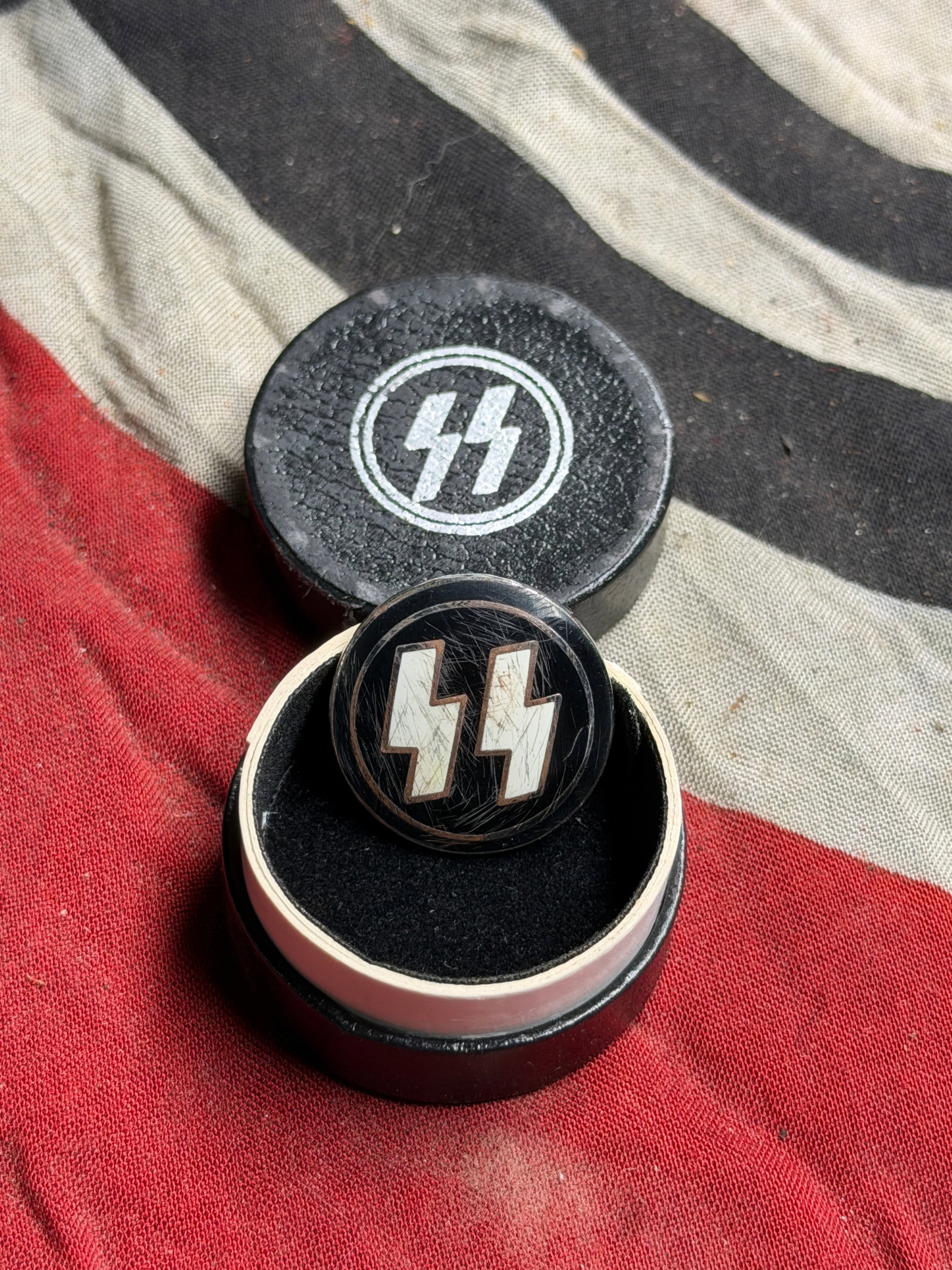 Cased WW2 German SS Membership Lapel Enameled Badge By Ges. Gesch. RZM M1/4: This circular badge, featuring the SS runes in white enamel on a black background, was the membership insignia of the Schutzstaffel (SS) — one of the most feared organizations within the Nazi regime