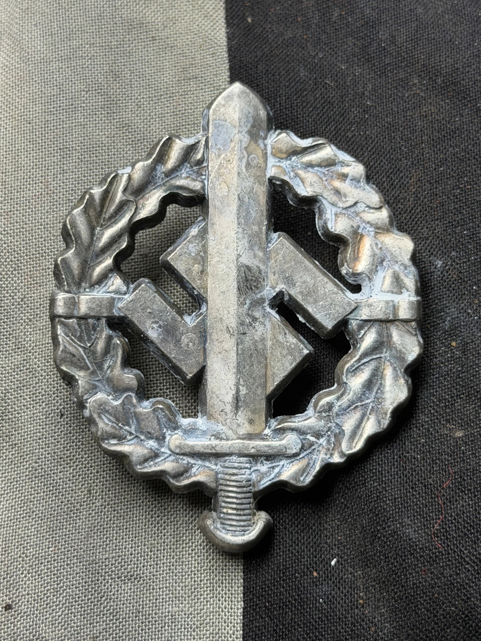 WW2 German SA Sports Badge (SA-Sportabzeichen) By W. Redo, Saarlautern: WW2 German SA Sports Badge (SA-Sportabzeichen) By W. Redo, Saarlautern. This metal badge, approximately 2 inches (5 cm) in height, depicts a vertically oriented sword superimposed upon a swastika, all