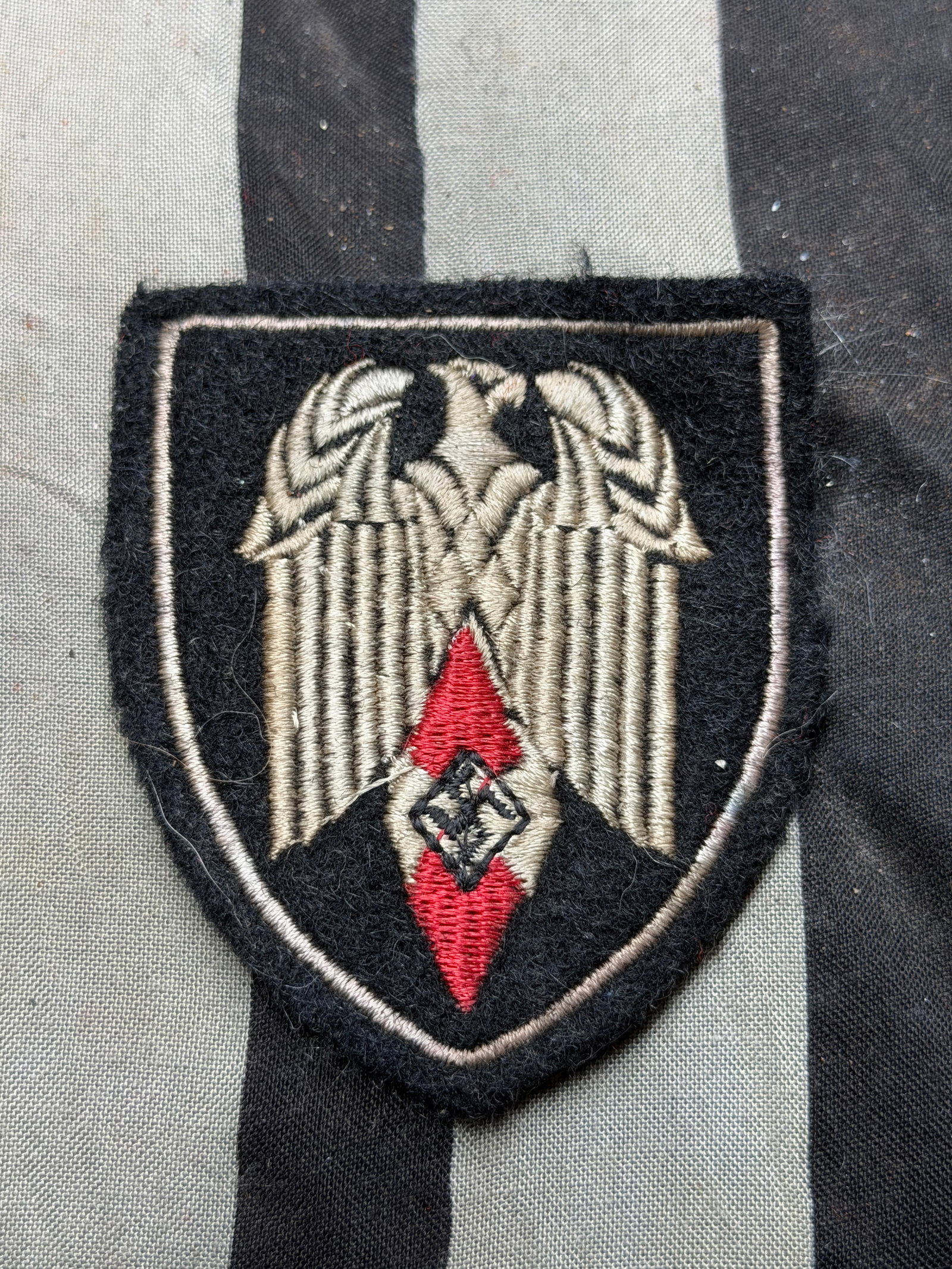 WW2 German Youth Organization Sleeve Insignia (c. 1930s–1940s): WW2 German Youth Organization Sleeve Insignia (c. 1930s–1940s). This embroidered sleeve patch features a stylized German eagle rendered in silver-gray thread above a red and black diamond-shaped fie
