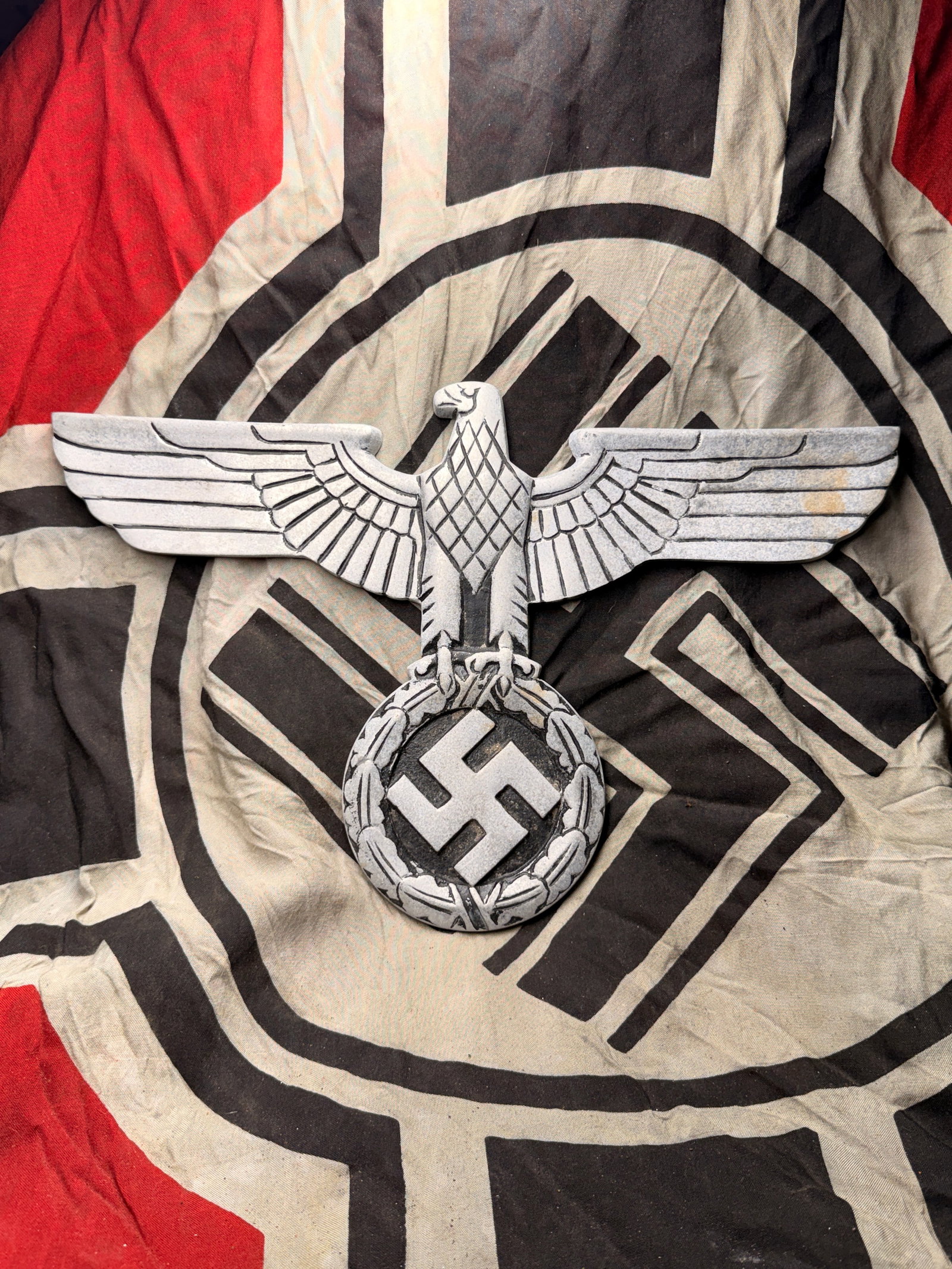 WW2 German Reich Eagle Plaque 1936–1945: This cast metal wall plaque depicts the Reichsadler, or Imperial Eagle, the official emblem of Nazi Germany from 1935 to 1945. The stylized eagle, wings outstretched, clutches a wreath enclosing a swa