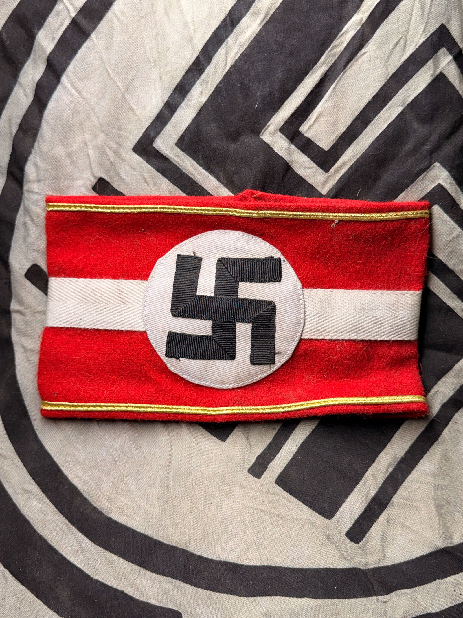 RARE WW2 GERMAN NSDAP POLITICAL LEADER ARMBAND WITH RZM PAPER TAG: RARE WW2 GERMAN NSDAP POLITICAL LEADER ARMBAND WITH RZM PAPER TAG. This is a Nazi Party (NSDAP) armband, featuring the infamous black swastika on a white roundel, set against a red wool background wit