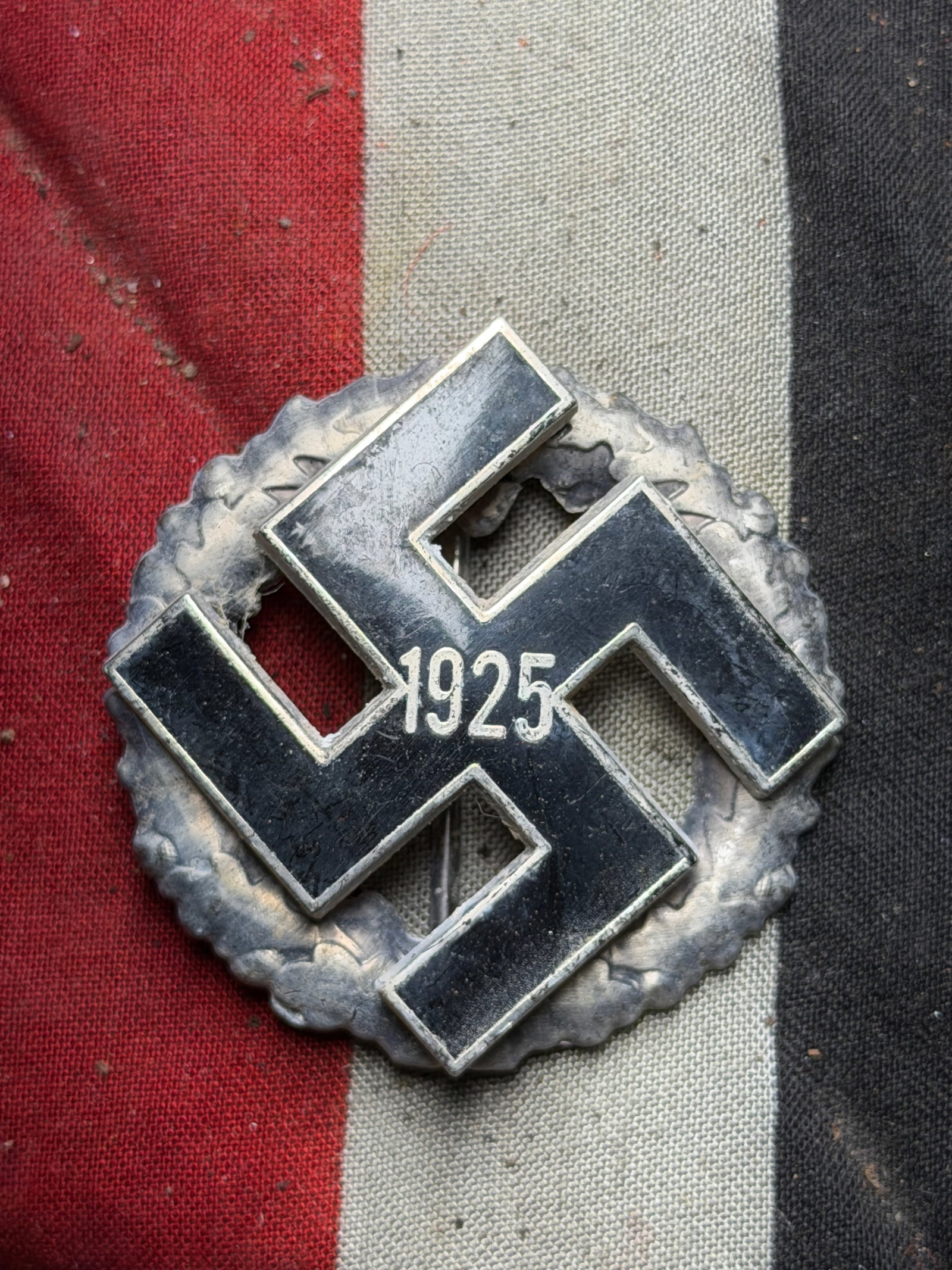 WW2 German “1925?? Party Membership Badge, circa early 1930s: This metallic badge features a large black swastika with the year “1925” inscribed at its center, encircled by a silvered oak-leaf wreath. Such insignia were issued to early members of the Nat