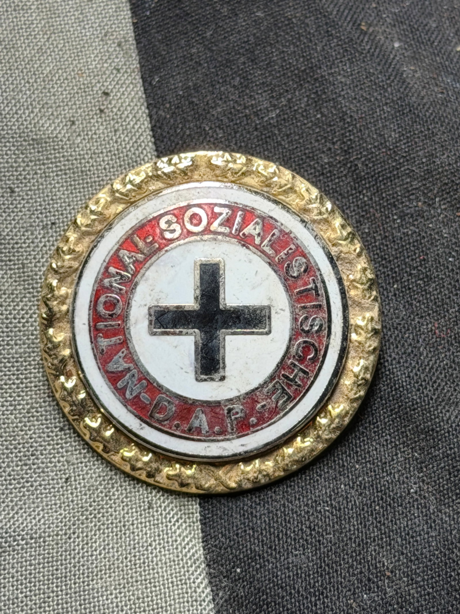 WW2 German Red Cross Badge – National Socialist People’s Welfare (NSDAP) Period By Ges. Gesch.: This is a German Red Cross (Deutsches Rotes Kreuz, DRK) badge dating from the National Socialist period (1930s–1940s). The badge features a central black cross on a white enamel field, surrounded by