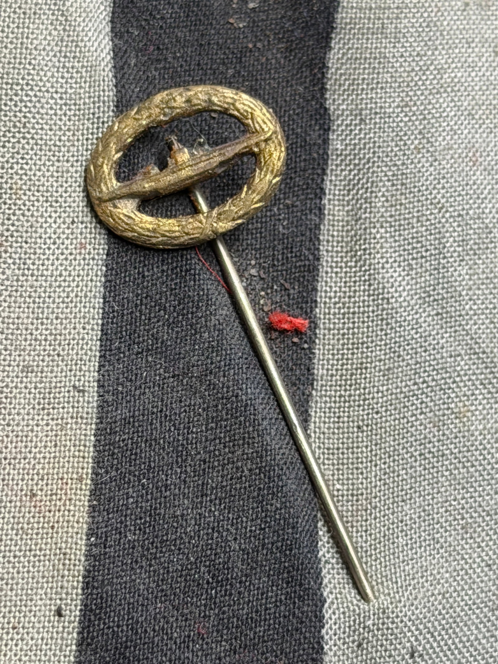 German Kriegsmarine U-Boat Badge Stickpin (World War II Period): This is a miniature Kriegsmarine U-Boat War Badge stickpin (U-Boots-Kriegsabzeichen), originating from Germany during the Second World War. The piece features a small oval wreath of laurel leaves surr