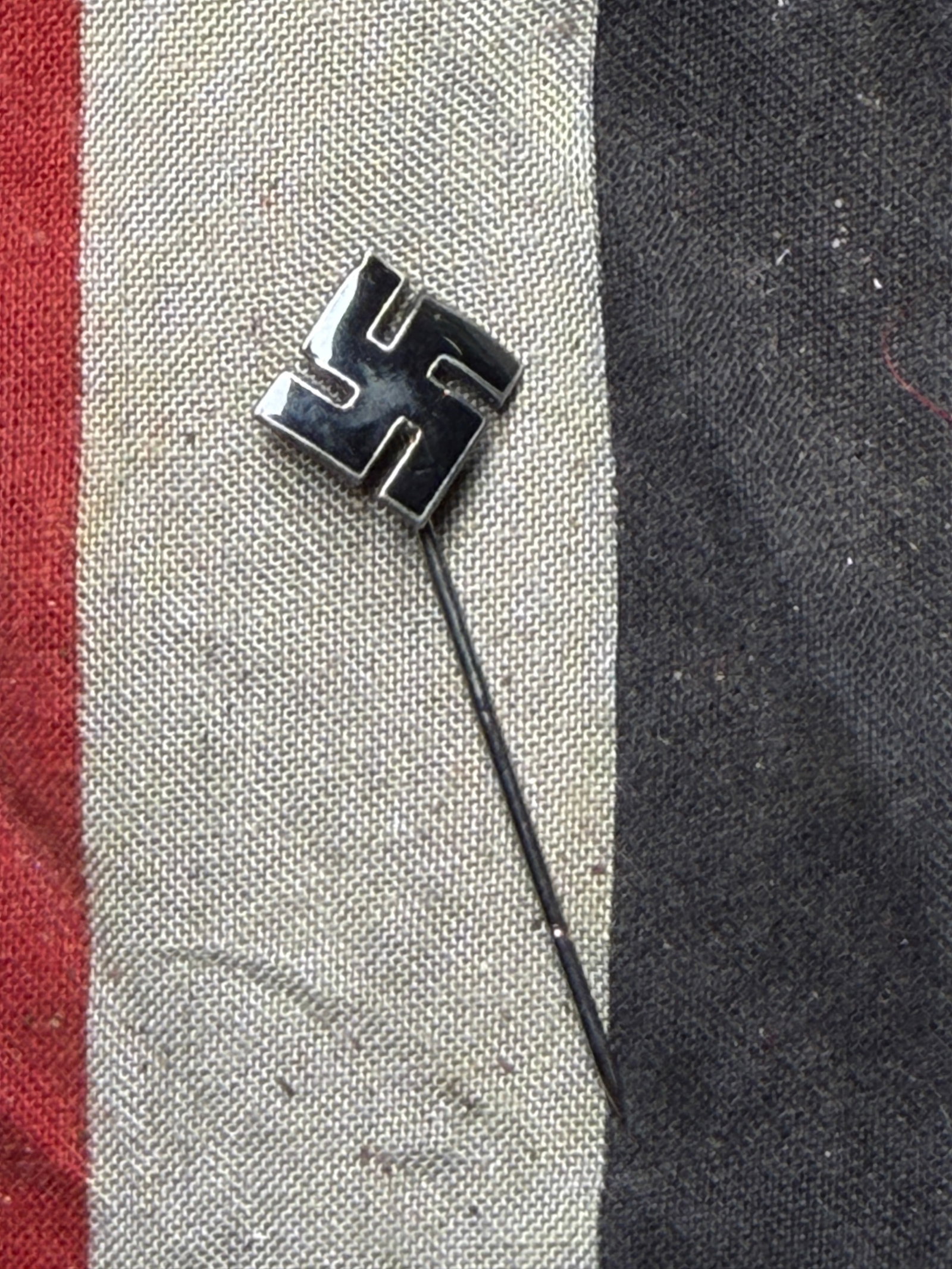 WW2 German Stickpin with Swastika Motif (Early 20th Century): This artifact is a metal stickpin featuring a swastika design, commonly used in Germany during the early to mid-20th century. The swastika, an ancient symbol found in many cultures worldwide, was appr