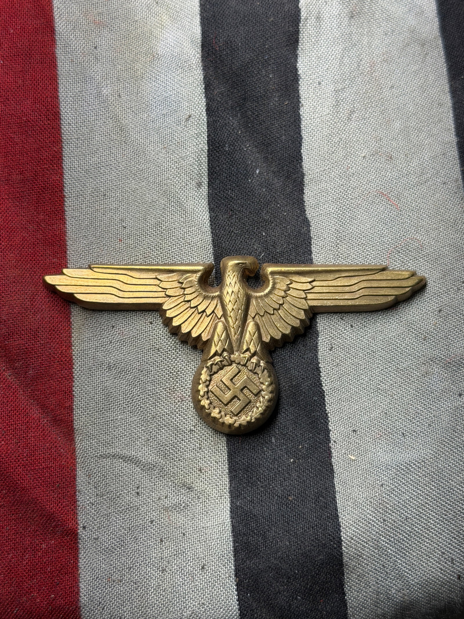 WW2 GERMAN WAFFEN SS EAGLE VISOR CAP BADGE: This is a cast brass emblem featuring an eagle with outstretched wings clutching a circular wreath. The emblem measures approximately 2.75 inches (7 cm) in width. Please view all detailed pictures. Co