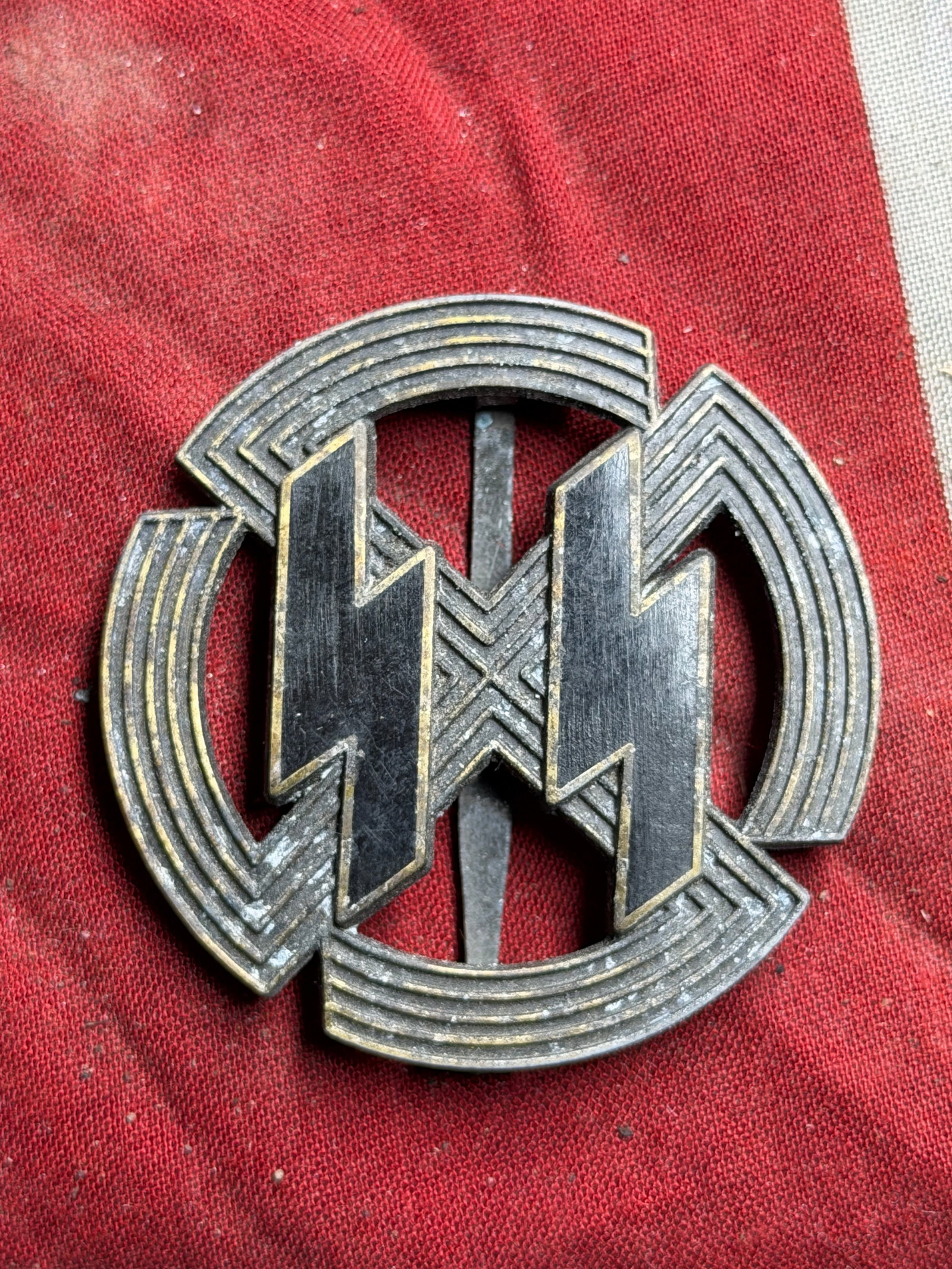 WWII German SS Proficiency Badge By Richard Sieper & Söhne, Lüdenscheid: This is a WWII-era metal proficiency badge, attributed to the Schutzstaffel (SS). The badge design features a double-rune motif enclosed within a circular, multi-tiered border. The reverse is maker-ma