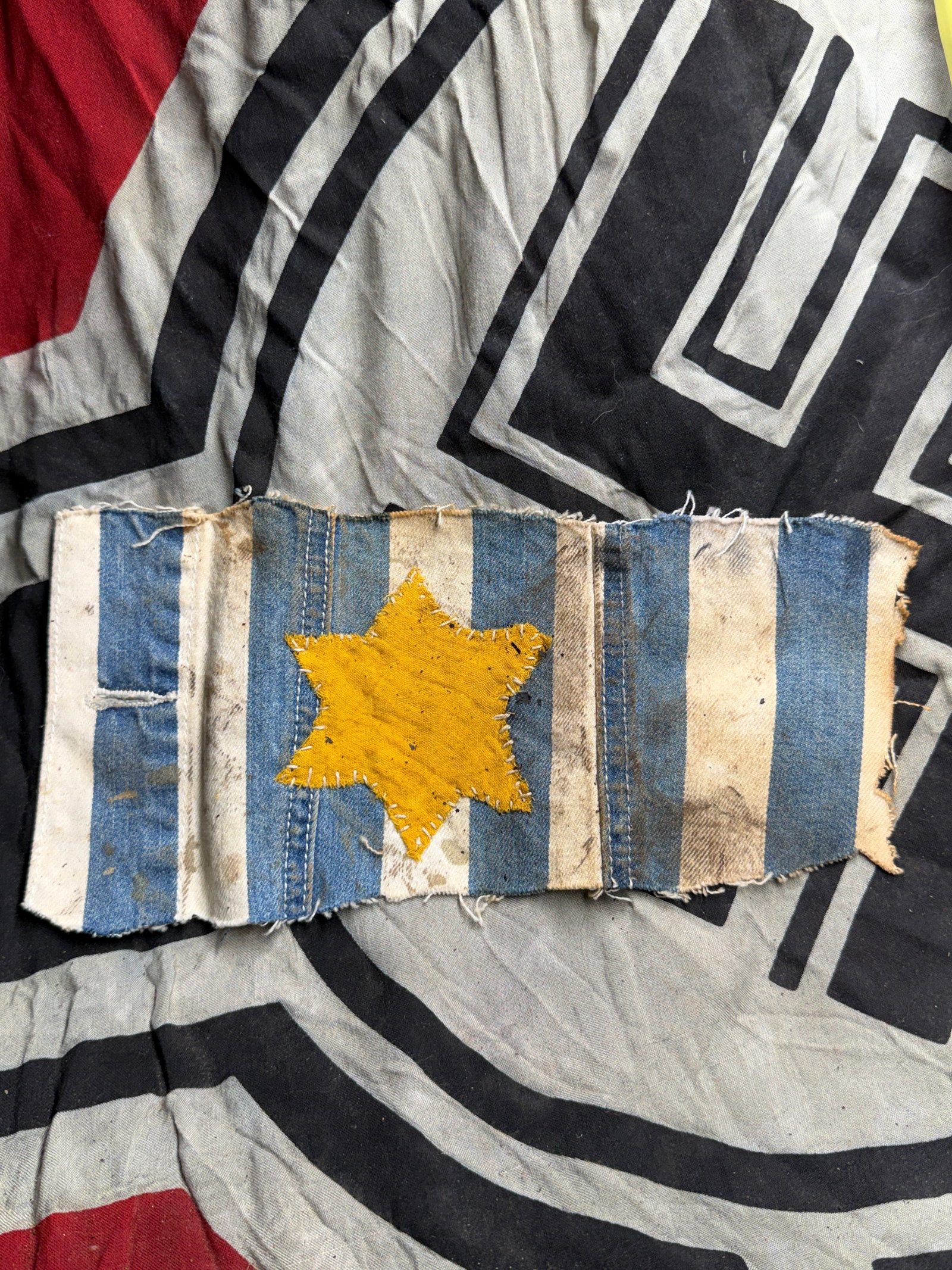 WW2 German Holocaust-Era Textile Armband with Yellow Star of David – Concentration Camp Artifact: This textile armband fragment dates from the period of the Holocaust (circa 1940–1945) and is believed to have originated from a concentration or forced labor camp. The piece is made of blue-and-whi