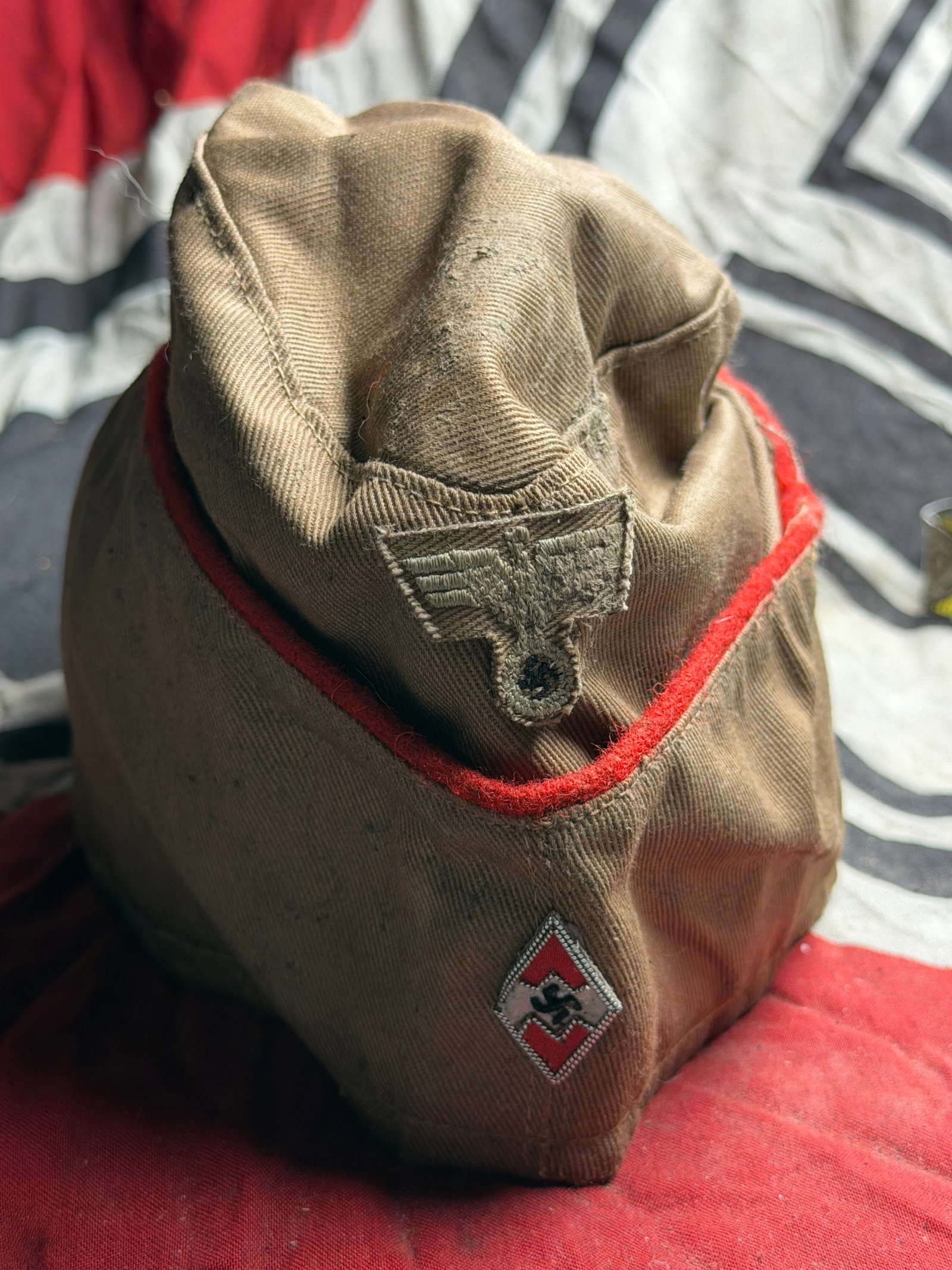 Rare WW2 German Hitler Youth Organization Side Cap, 1930s–1940s With RZM Paper Tag: This tan fabric side cap with red piping and insignia belonged to a youth organization operating in Germany during the Nazi period. Has the RZM Paper Tag attached to the inside. The cap features a nat