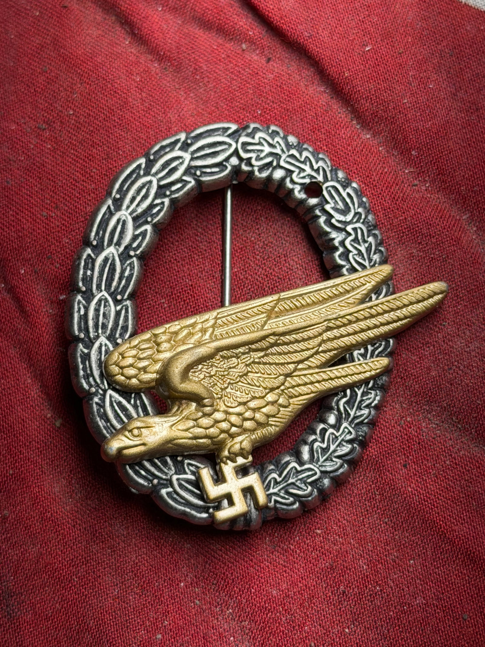 Rare WW2 German Luftwaffe Paratrooper Badge: This metal badge features a gilt eagle in flight surrounded by an oxidized silver wreath of oak and laurel leaves. It was issued during the Nazi era in Germany to signify qualification within the Luft