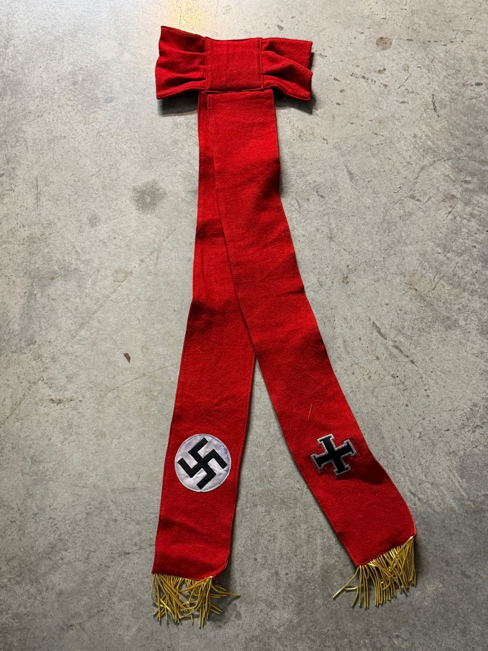 WW2 GERMAN NSDAP IRON CROSS FUNERAL SASH: WW2 GERMAN NSDAP IRON CROSS FUNERAL SASH. This red wool ceremonial drape features an attached bow at the top and two long hanging panels ending in gold fringe. Each panel bears an emblem: one with a b