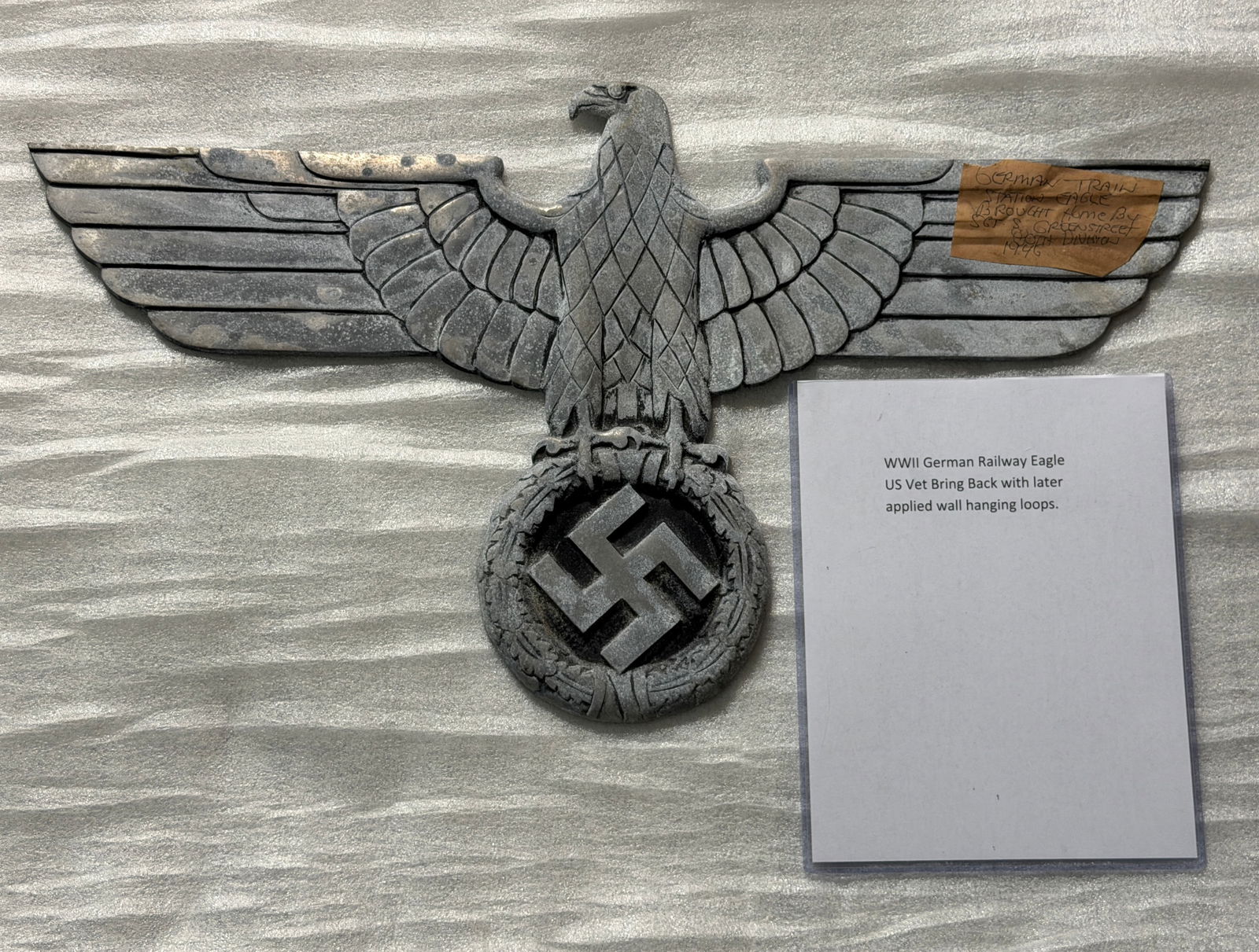 Vet Bring Back WW2 German Railway Eagle, c. 1930s–1940s: This cast-aluminum eagle emblem, originally mounted on German railway buildings during the period of Nazi rule, features the stylized national eagle clutching a wreath enclosing a swastika. The emblem
