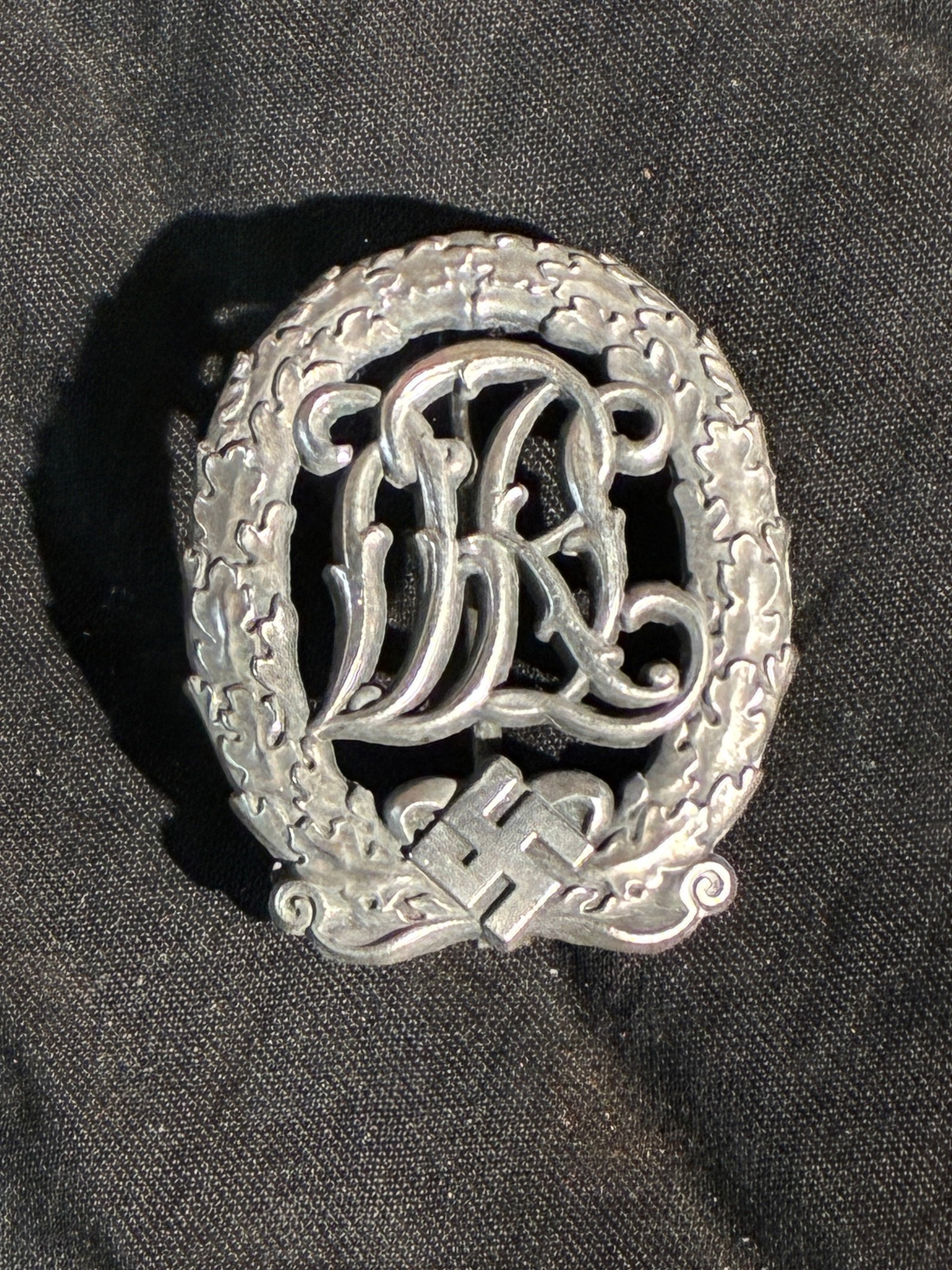 WW2 German Sports Badge for War Disabled (DRL Variant) By DRGM: This badge is modeled after the Deutsches Reichssportabzeichen (German National Sports Badge), featuring an ornate wreath encircling the intertwined “DRL” monogram—an abbreviation for Deutsc