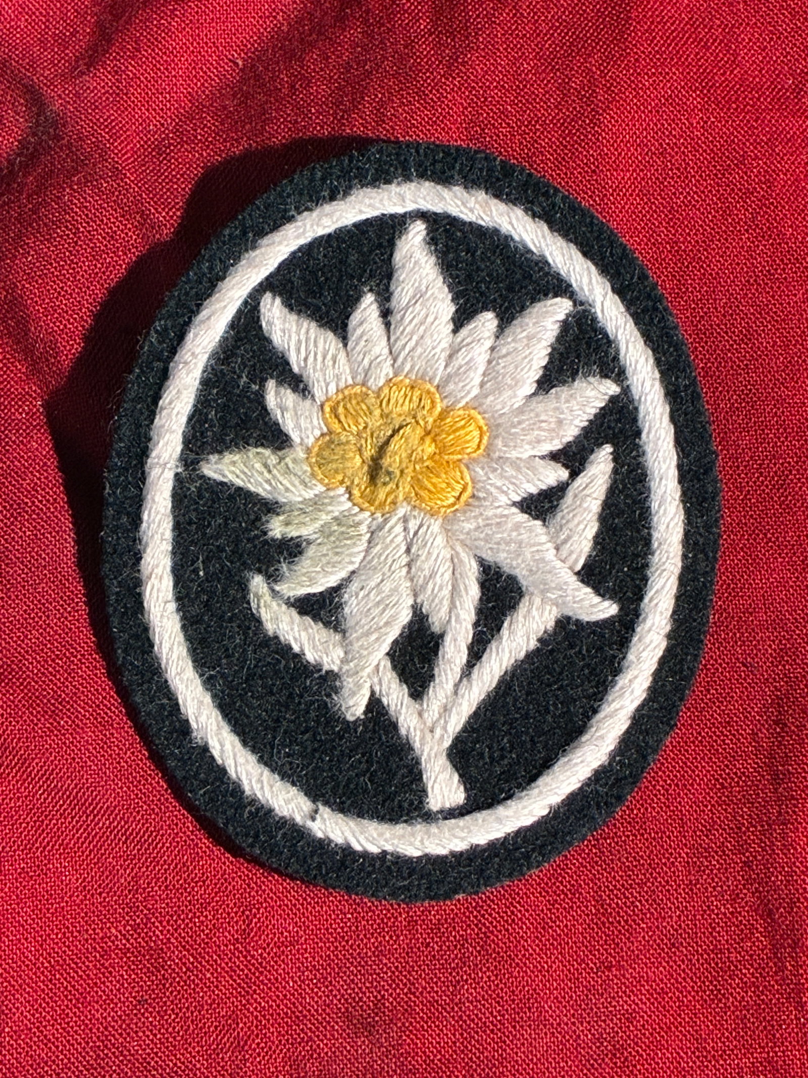WW2 German Gebirgsjäger Edelweiss Sleeve Insignia (Alpine Troops): This embroidered cloth insignia features the Edelweiss flower, the traditional emblem of Germany’s Gebirgsjäger, or mountain infantry. Worn on the sleeve of the uniform, the Edelweiss symbolized th