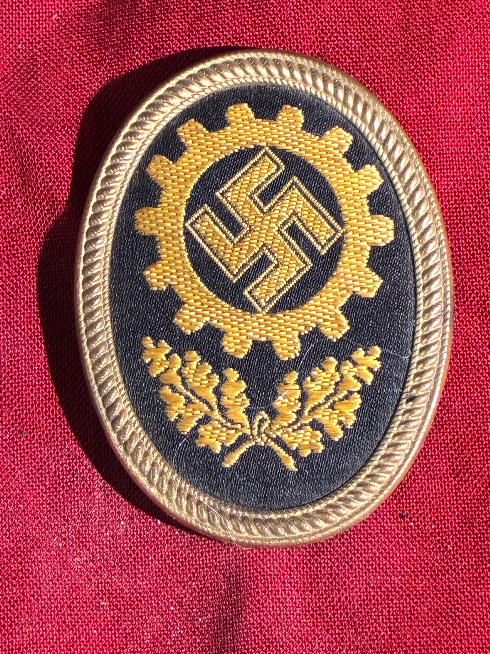 WW2 German Labor Front (DAF) Visor Cap Badge – Third Reich Period: This badge originates from the Deutsche Arbeitsfront (DAF), or German Labor Front, the compulsory labor organization established by the Nazi regime after the dissolution of independent trade unions in