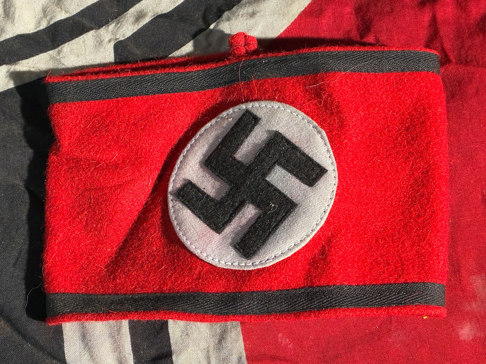 WW2 German Waffen SS Armband with RZM Label (“Reichsführer-SS befohlene Ausführung??): This armband is a red wool band bearing a black swastika within a white oval field, bordered at the top and bottom by black cloth stripes. On the inside is a pair of woven RZM (Reichszeugmeisterei) la