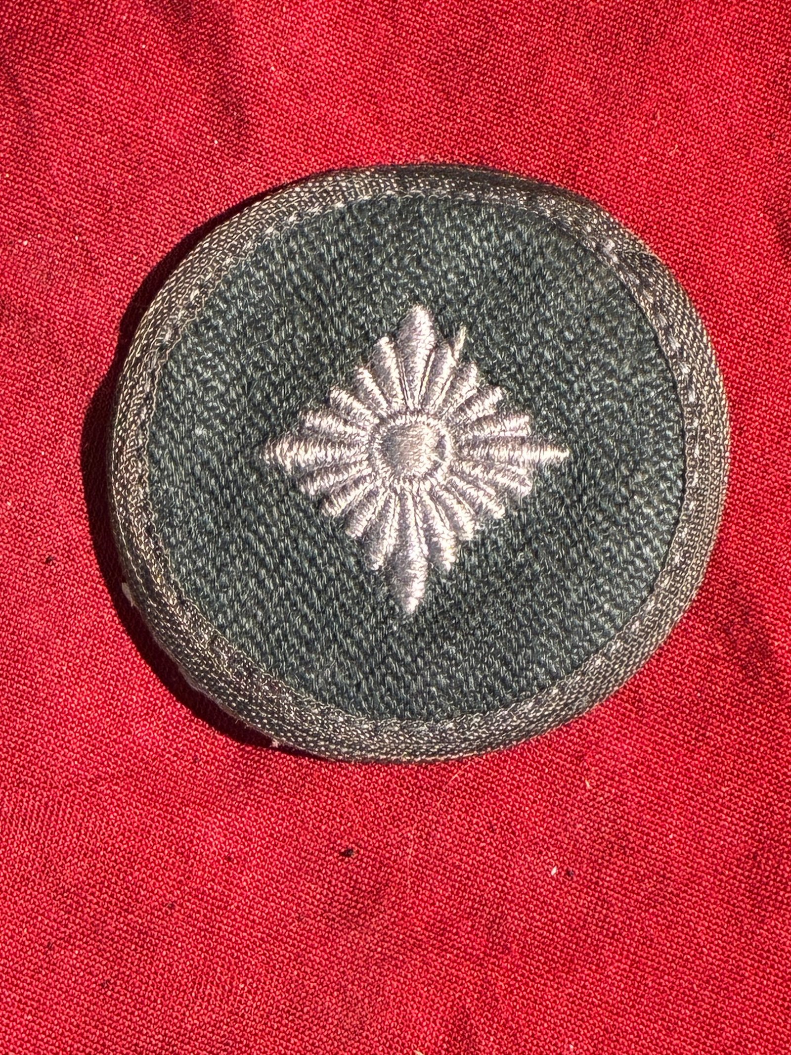 WW2 German Police Sleeve Rank Insignia (Likely Meister Rank), c. 1936–1945: This circular embroidered patch is an original sleeve rank insignia worn by members of the German Ordnungspolizei (Order Police) during the Nazi era. The insignia features a silver-grey embroidered ei