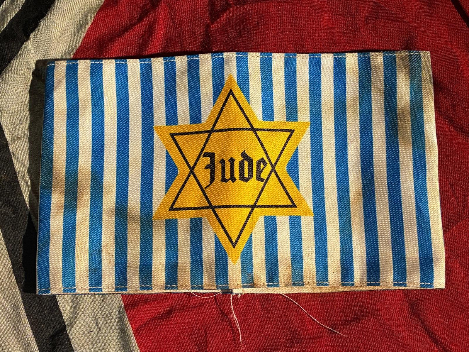 RARE WW2 GERMAN JEWISH STAR OF DAVID JUDE CONCENTRATION CAMP ARMBAND: RARE WW2 GERMAN JEWISH STAR OF DAVID JUDE CONCENTRATION CAMP ARMBAND. This armband, featuring a printed yellow Star of David labeled “Jude”, imitates the compulsory identification badges force