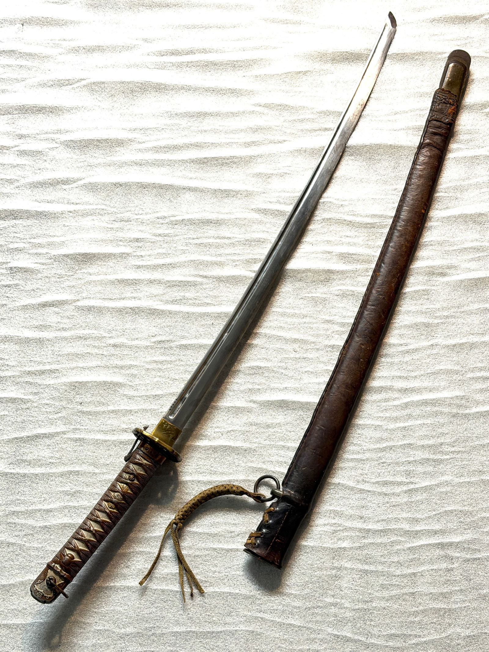 Imperial Japanese Army Officer’s Shin-Gunt? (Type 98) with Leather-Covered Combat Scabbard: This sword is a Type 98 Shin-gunt?, the regulation sidearm worn by commissioned officers of the Imperial Japanese Army during the Second World War. Modeled aesthetically after the traditional katana,