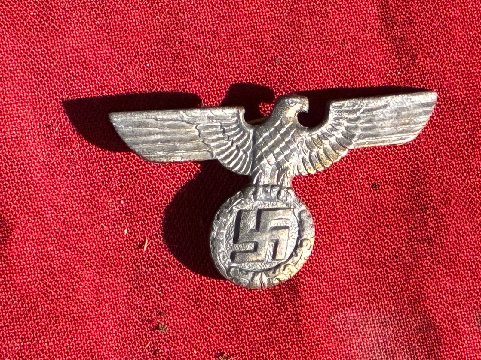 WW2 German NSDAP Party Member’s Eagle Pin (RZM Marked, M1/77): This small metal pin features the stylized eagle and swastika emblem used by the National Socialist German Workers’ Party (NSDAP) in Germany during the Third Reich. Such insignia were commonly worn 