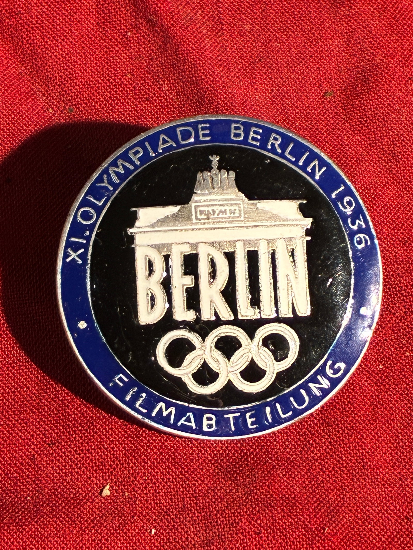 WW2 German 1936 Berlin Olympics Film Department Badge (Blue Variant): This circular enamel badge was issued to members of the Filmabteilung (Film Department) during the 1936 Summer Olympics in Berlin, an event heavily utilized by the Nazi regime for propaganda. The badg