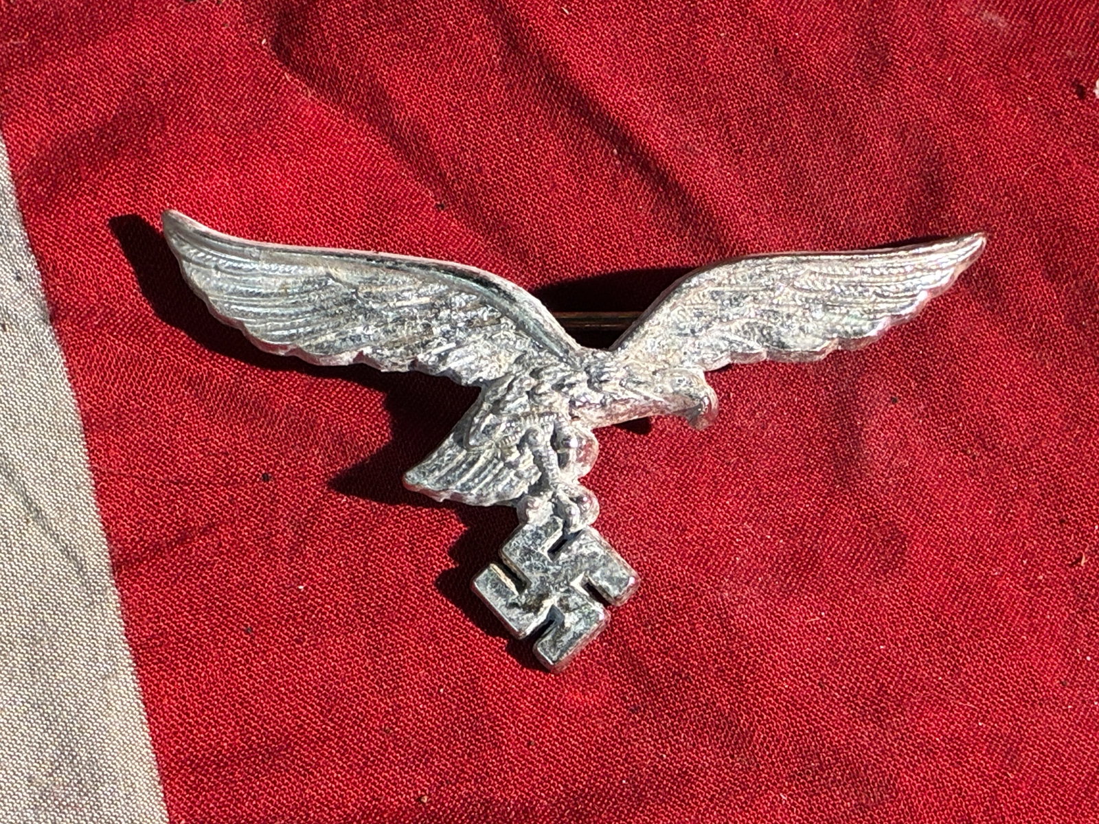 WW2 German Luftwaffe Cap Eagle (Pin-Back Variant), ca. 1935–1945: This metal insignia—depicting the German Luftwaffe’s stylized eagle clutching a swastika—was worn on headgear by personnel of Nazi Germany’s air force during the period of the Third Reich (193