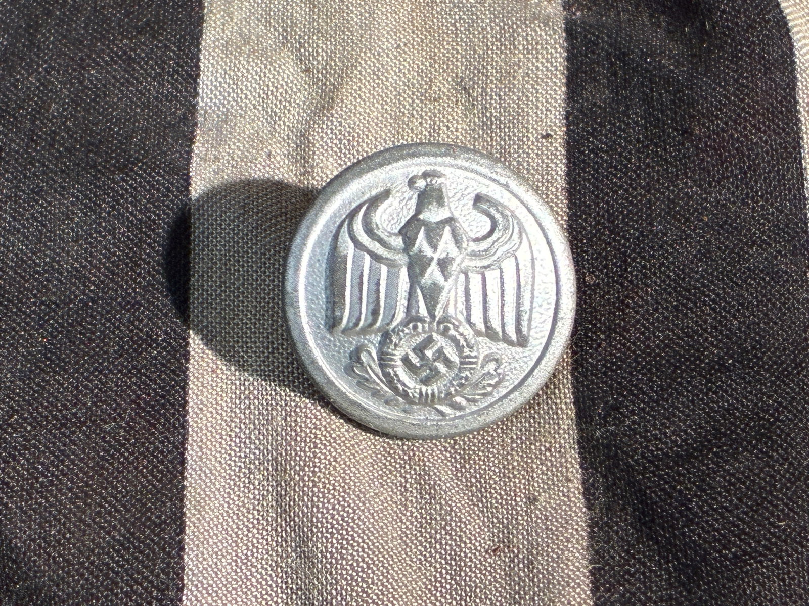 German Police Uniform Button (Third Reich Period), c. 1936–1945: This small aluminum button features the stylized national eagle used by German state police organizations during the era of the Third Reich. The design includes an eagle with outstretched wings clutch