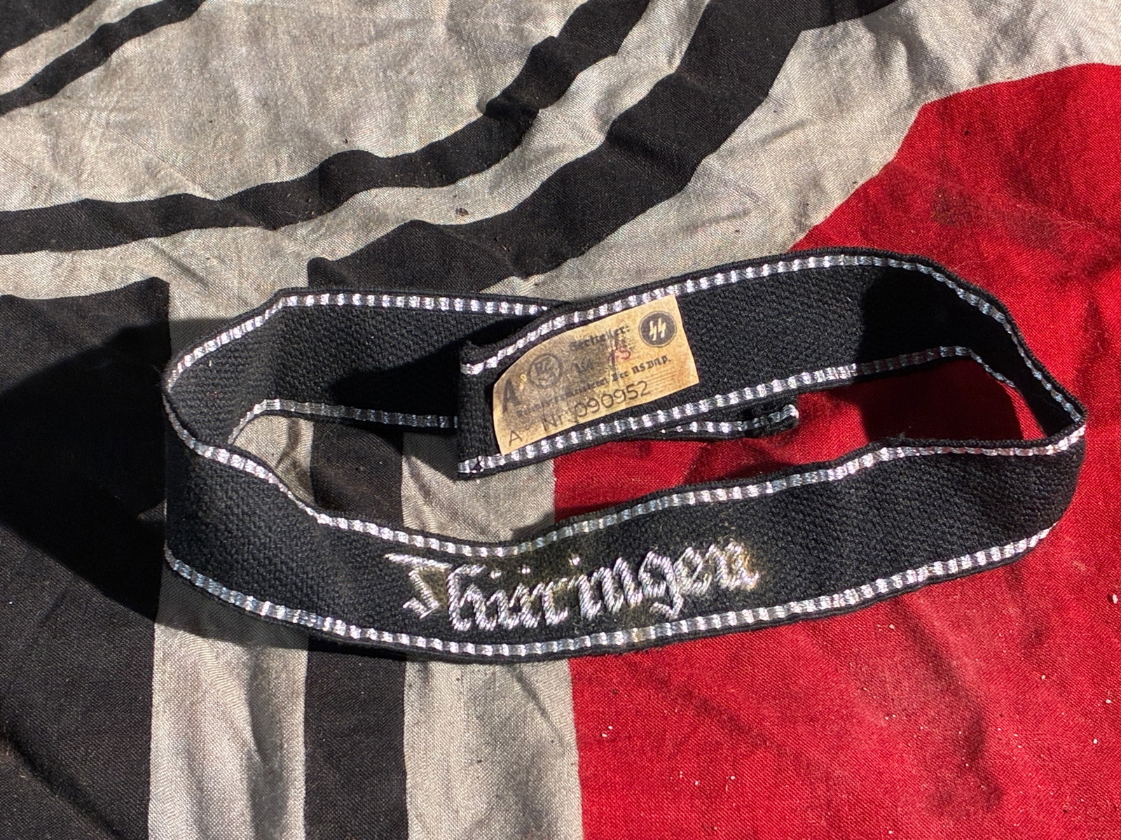 WW2 German Waffen-SS “Thüringen?? Cuff Title (Uniform Sleeve Insignia), with RZM Label: This textile cuff title, embroidered with the word “Thüringen,” is a uniform insignia issued to personnel of a Waffen-SS unit associated with the German region of Thuringia during the Second 