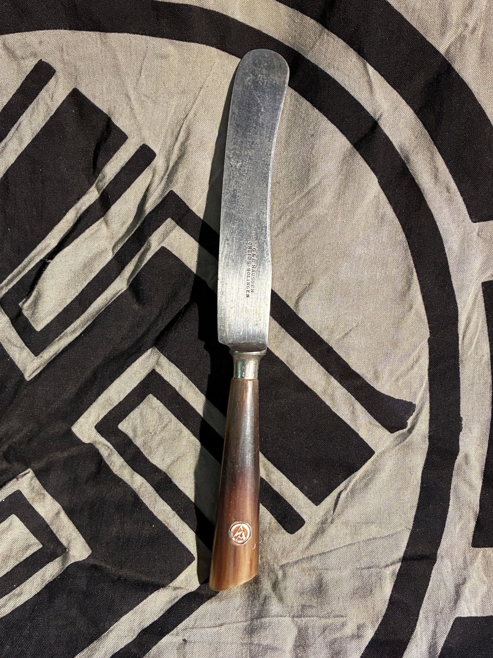 WW2 German SA Presentation Knife with Horn Handle and Maker’s Mark, ca. 1930s–1940s: This table knife, produced by C.&E. Hüsgen, Ohligs–Solingen, features a polished horn handle inset with the insignia of the Sturmabteilung (SA), the paramilitary wing of the National Socialist Part