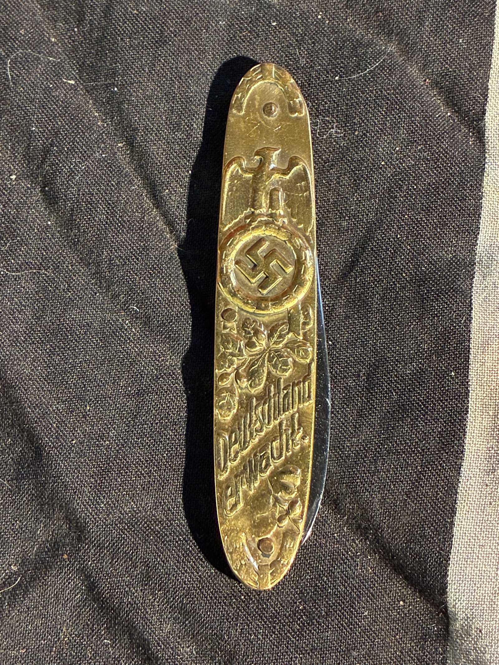 WW2 German Propaganda Pocket Knife Featuring Nazi Emblems and Adolf Hitler Portrait (c.: This small brass-handled pocket knife is an example of mass-produced propaganda merchandise distributed in Nazi Germany during the 1930s–1940s. The handle features prominently engraved imagery assoc