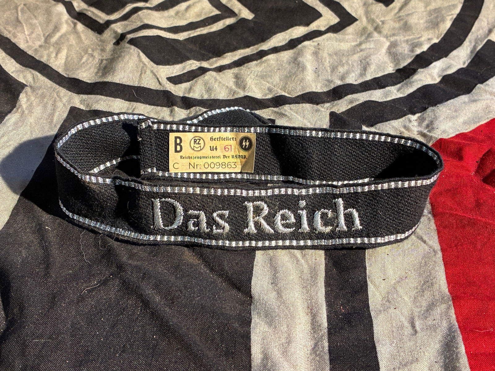 WW2 German Waffen-SS “Das Reich?? Cuff Title With RZM Paper Tag: This cuff title bears the embroidered designation “Das Reich,” identifying the 2nd SS Panzer Division, a formation of the Waffen-SS during the Second World War. The band is constructed of blac