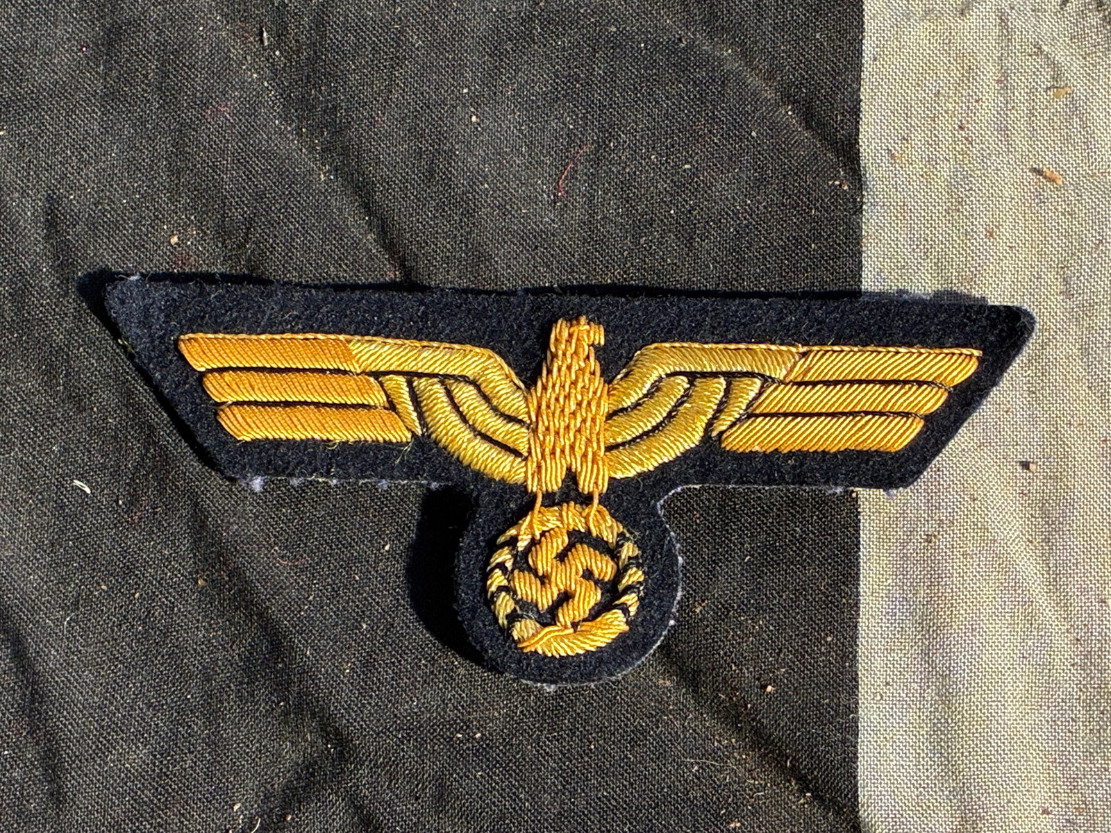 WW2 German Waffen-SS Officer’s Sleeve Eagle (Gold Wire Variant): This sleeve insignia represents the Waffen-SS officer’s national emblem, worn on the upper left sleeve of the field-grey service tunic. The design features a stylized German eagle clutching a wreath