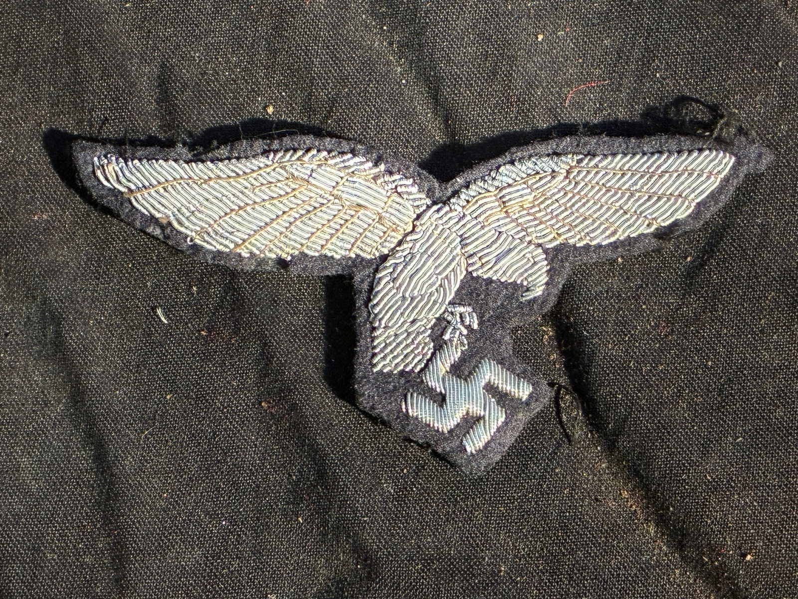 WW2 German Luftwaffe Officer’s Bullion Breast Eagle (Original Variant), 1935–1945: This hand-embroidered breast eagle was worn by officers of the German Luftwaffe (Air Force) during the Third Reich. Executed in fine silver bullion wire on dark blue-grey wool backing, the insignia de
