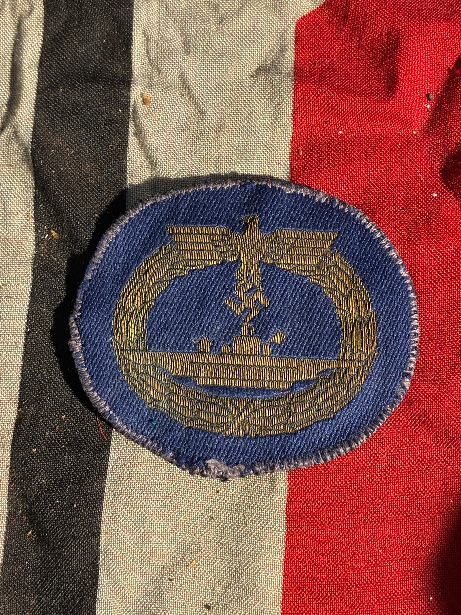 Kriegsmarine Coastal Artillery Proficiency Patch (Germany, WWII): This oval cloth badge was worn by members of the Kriegsmarine (German Navy) serving in coastal artillery units during the Second World War. Embroidered in gold thread on dark blue cloth, the design fe