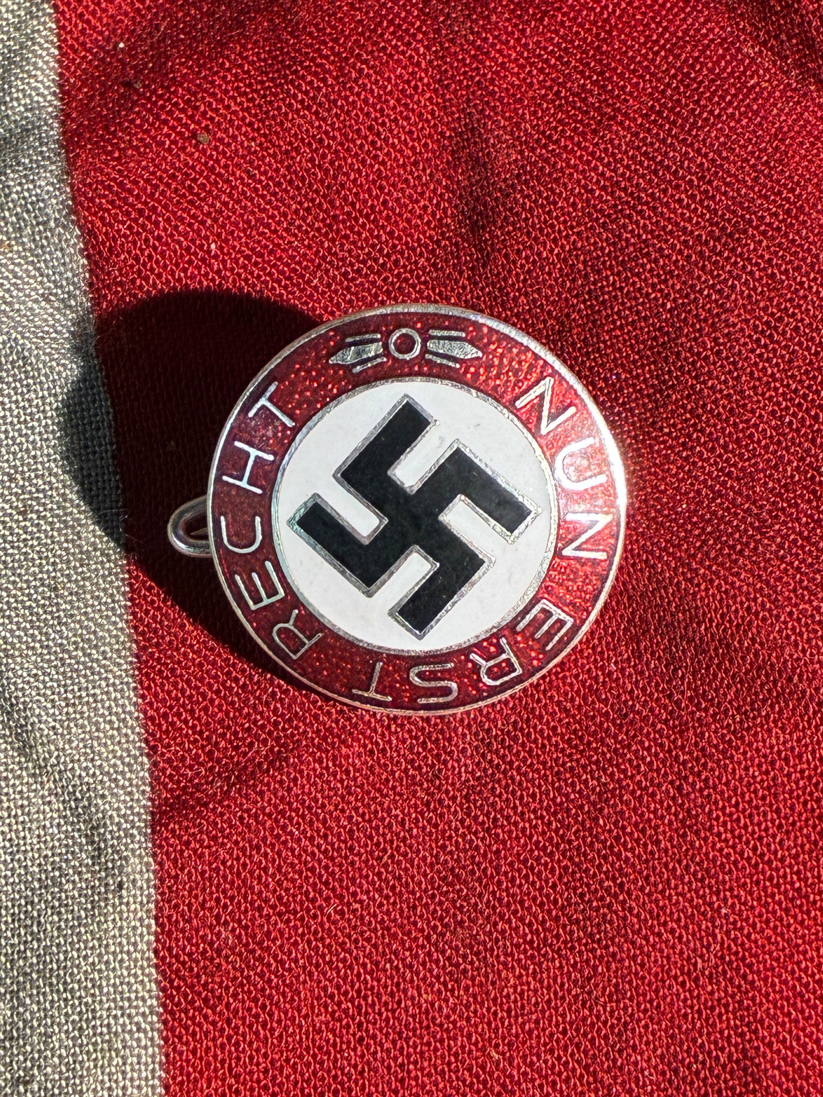 WW2 German Propaganda Badge: “Nun Erst Recht?? (c. 1930s–1940s) By Ges. Gesch.: This circular enamel badge features the slogan “Nun Erst Recht” (“Now More Than Ever”) surrounding a prominent swastika—an emblem widely used by the National Socialist regime. Such b