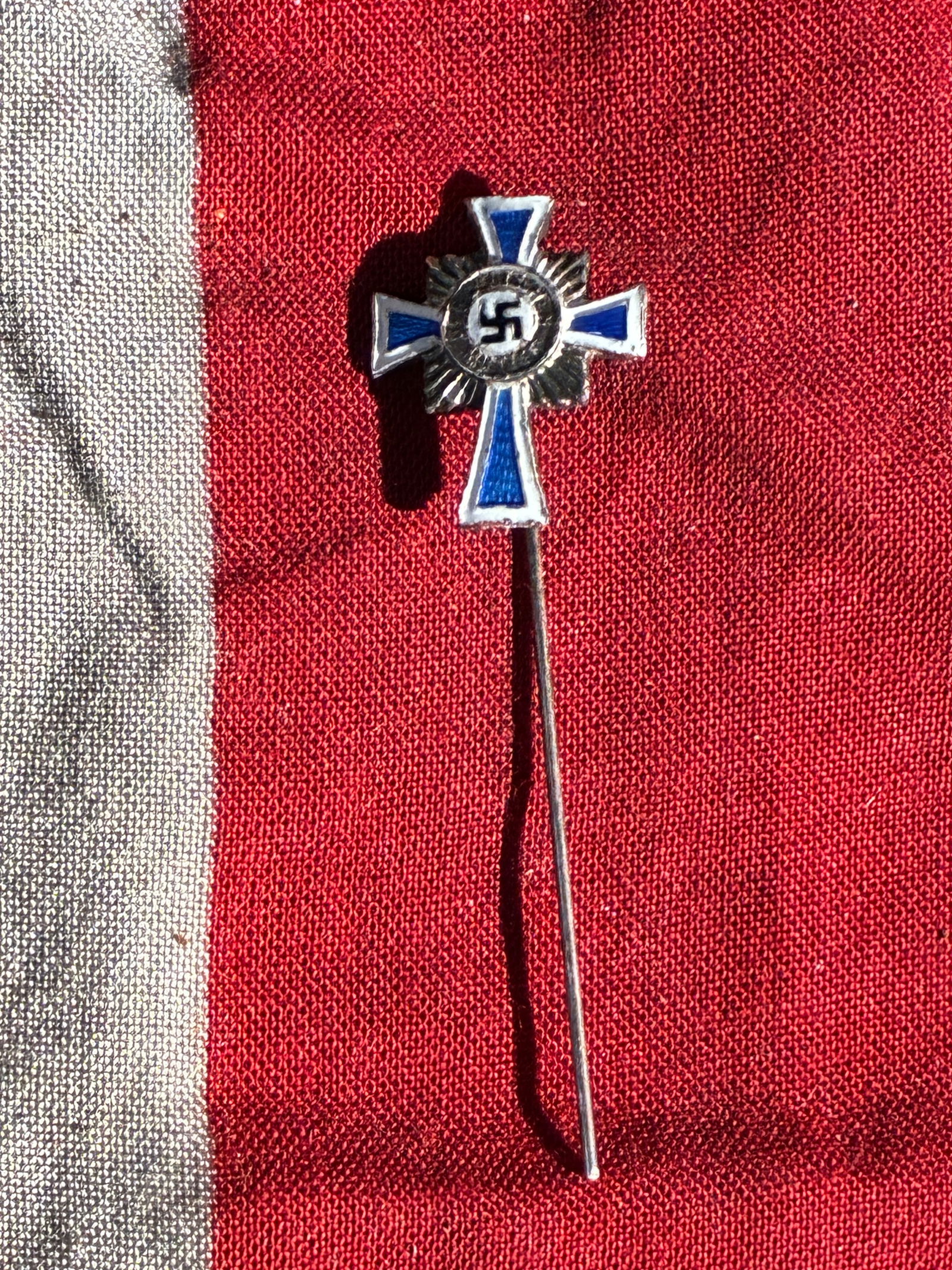German Mother’s Cross (Mutterkreuz) – Miniature Stickpin Version (c. 1938–1945): This miniature stickpin represents the Ehrenkreuz der Deutschen Mutter (“Honor Cross of the German Mother”), a state decoration instituted in 1938 by the Nazi regime to encourage large Aryan f