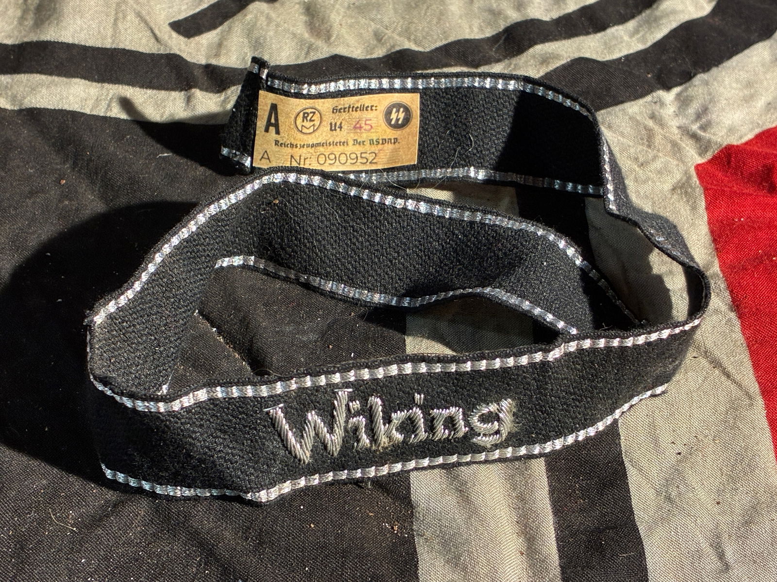 WW2 German Waffen-SS “Wiking?? Cuff Title (Uniform Insignia), ca. 1940–1945 With RZM Paper Tag: This black fabric cuff title, embroidered with the word “Wiking” in silver thread, was worn as a uniform distinction by members of the 5th SS Panzer Division “Wiking,” a mechanized com