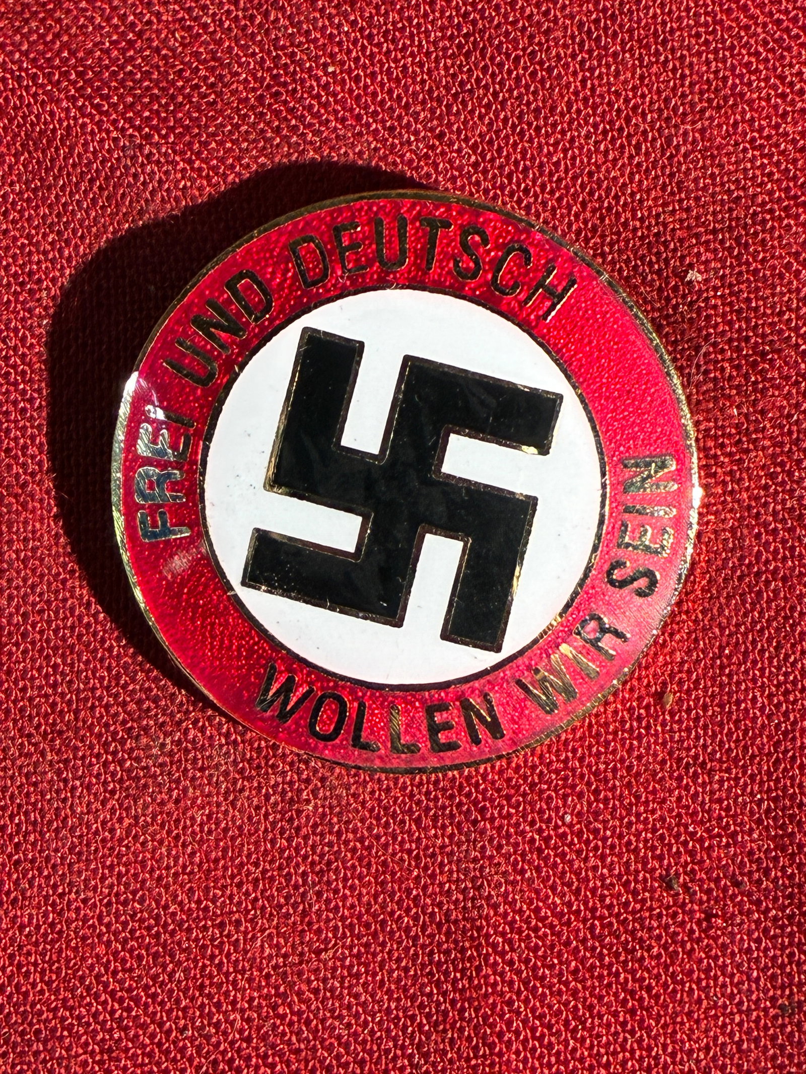 WW2 German Propaganda Membership Badge “Frei und Deutsch Wollen Wir Sein?? By Ges. Gesch.: This circular enameled badge features a prominent swastika at its center, surrounded by the slogan “Frei und Deutsch Wollen Wir Sein” (“Free and German We Want to Be”). Produced during